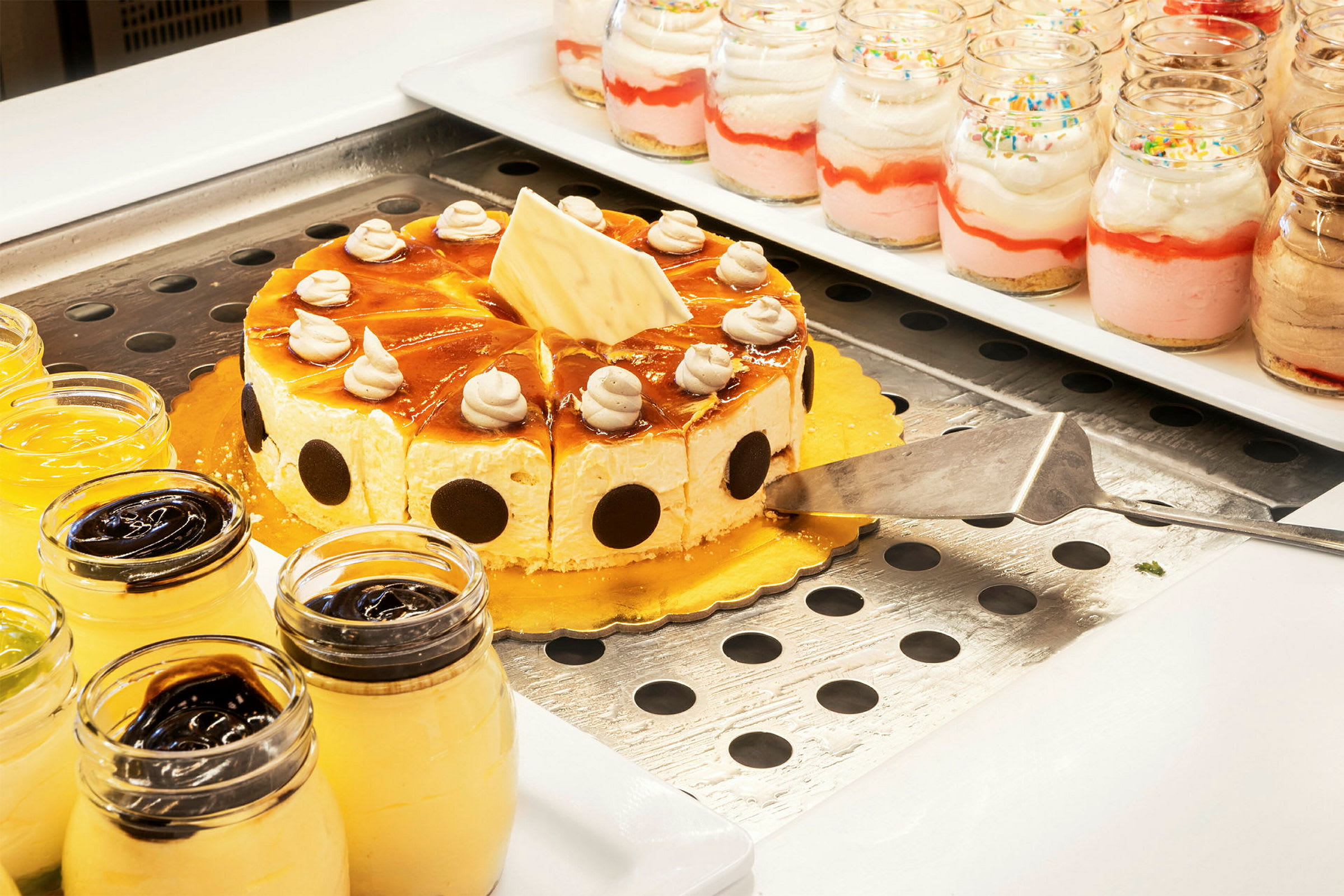 Bilde av et bord med forskjellige desserter, inkludert en kake med glasur og dessertglass. (AI-generert tekst)