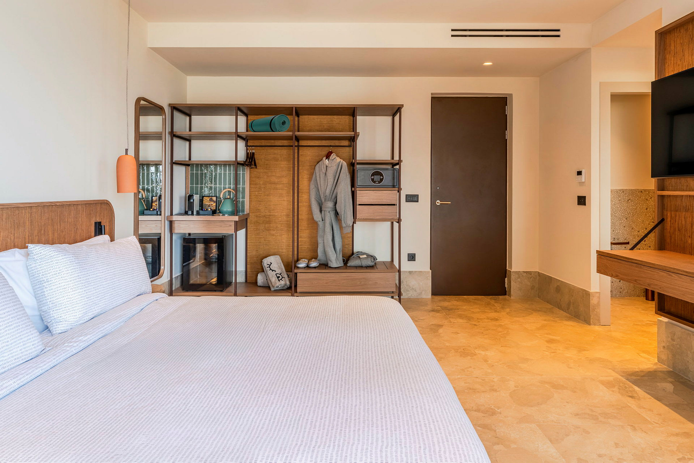 Et hotellrom med en stor seng, tremøbler og en åpen garderobe. (AI-generert tekst)