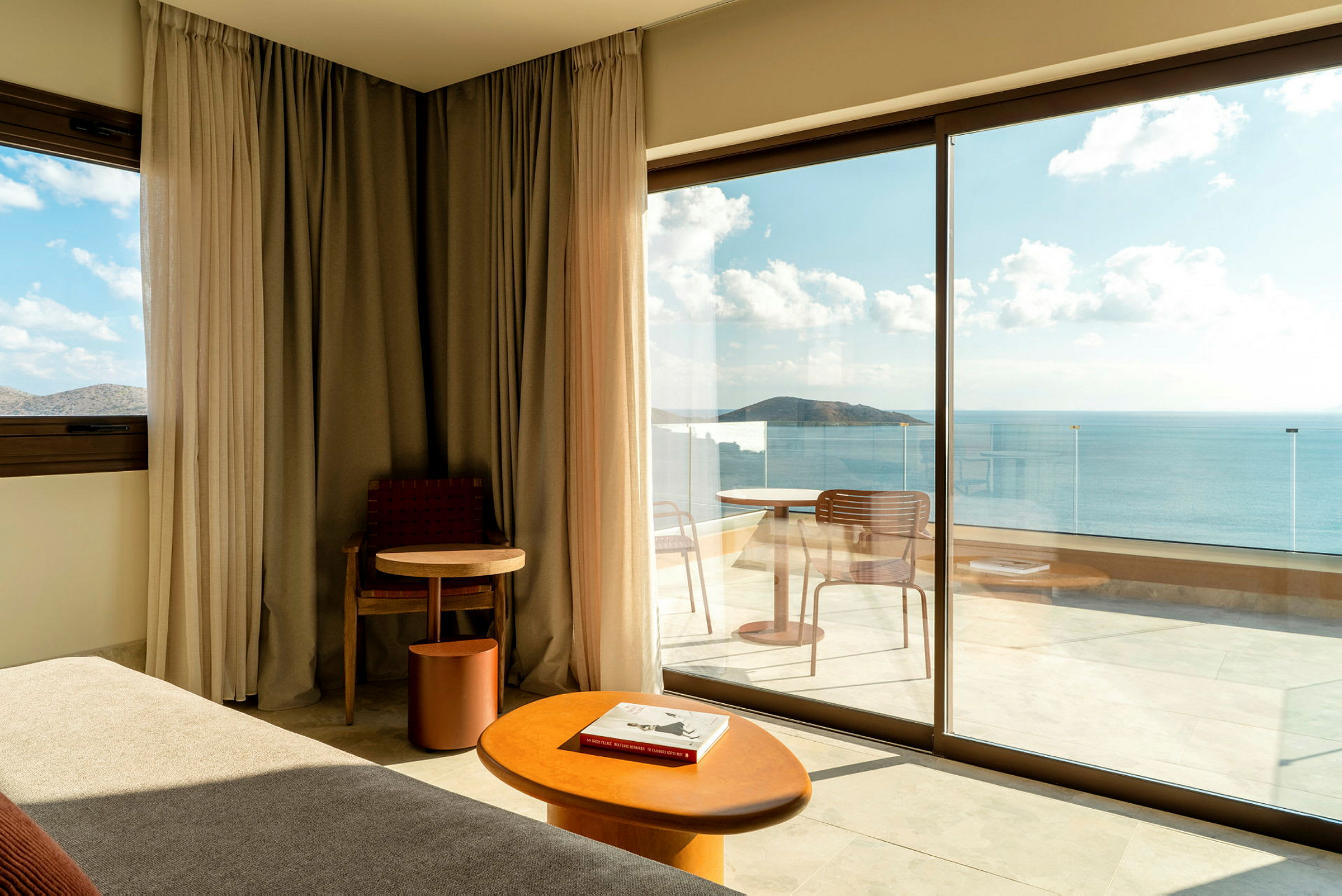 Moderne hotellrom med store glassdører som vender ut mot en balkong med havutsikt. (AI-generert tekst)