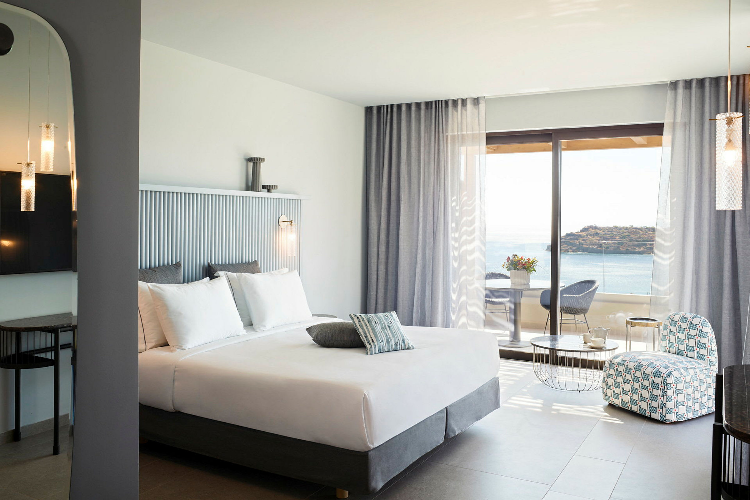 Hotellrom med dobbeltseng, sittegruppe og utsikt over havet. (AI-generert tekst)