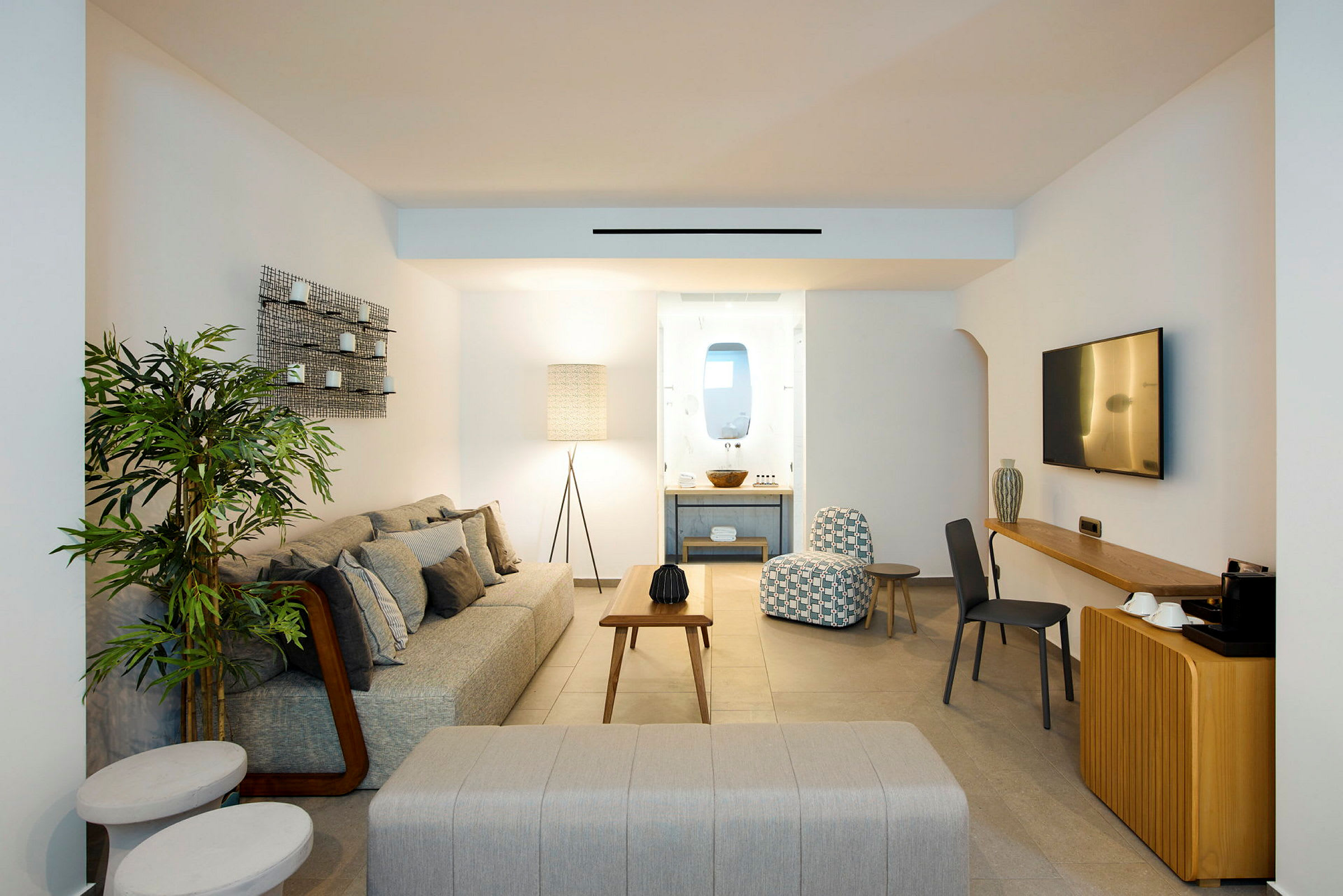 Moderne innredet stuedel i hotellrom med sofaer, bord og dekorativ belysning. (AI-generert tekst)