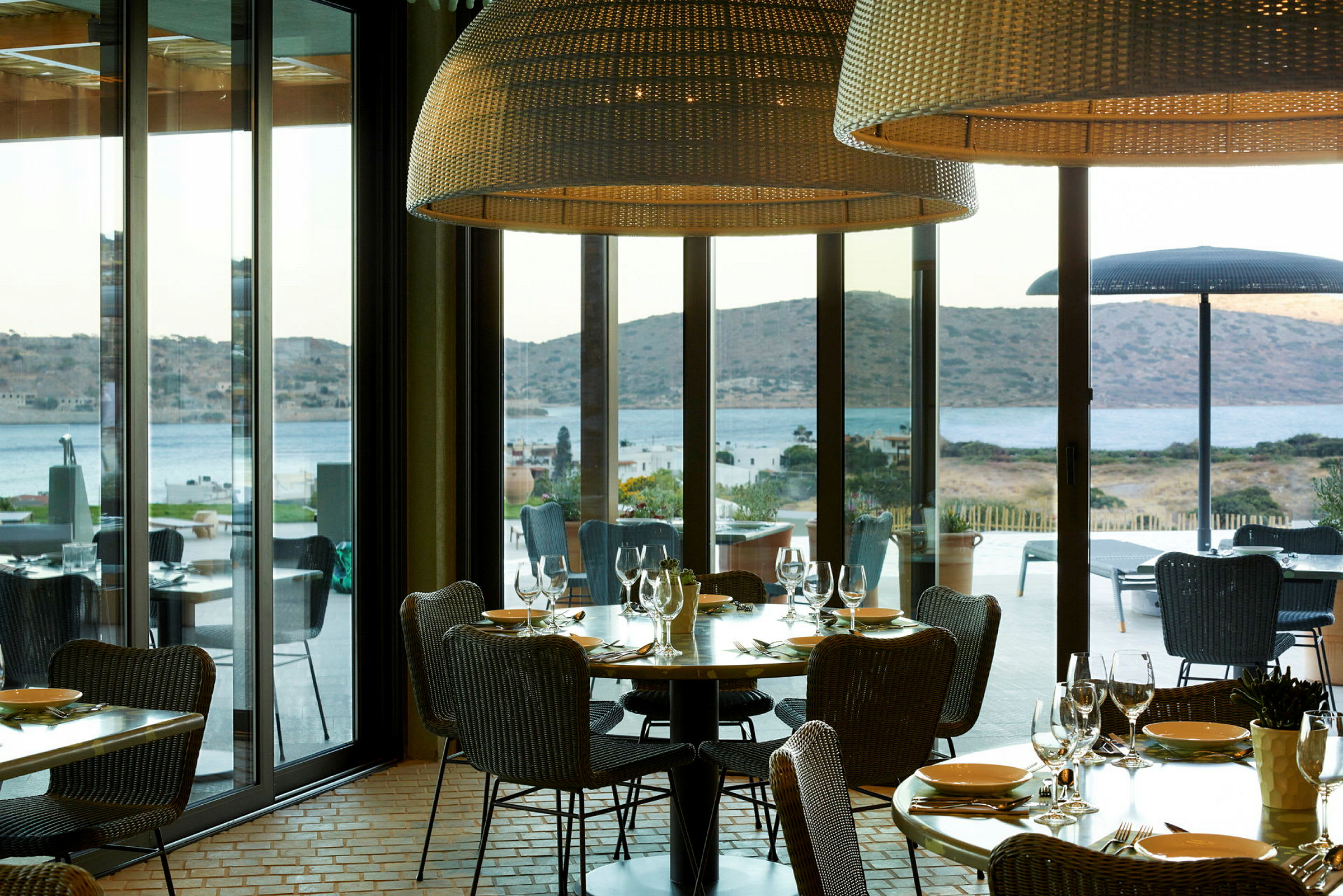 Restaurant med utsikt over sjøen og fjell gjennom store vinduer. (AI-generert tekst)