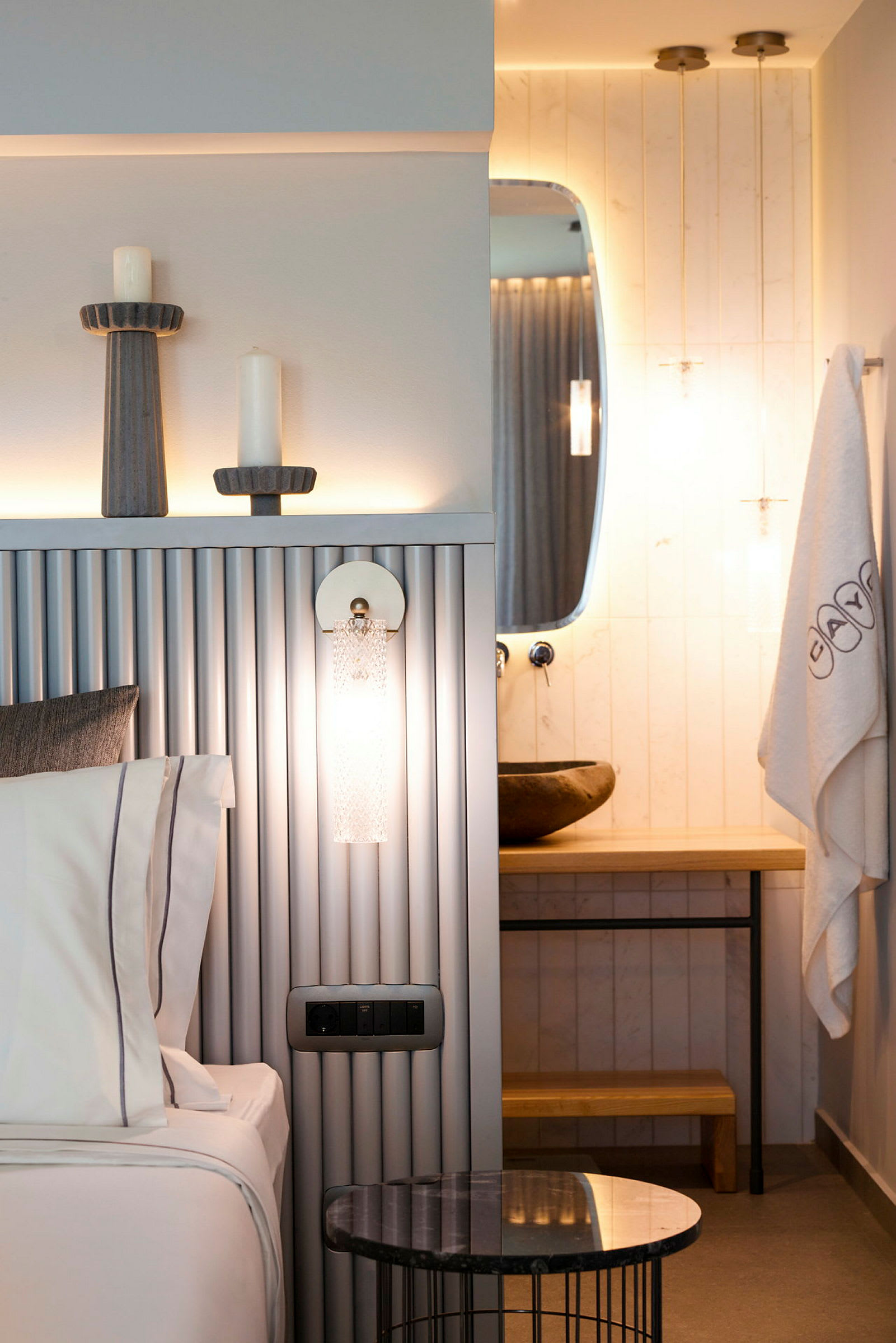 Et moderne hotellrom med en seng, et dekorativt bord og et bad med et speil. (AI-generert tekst)