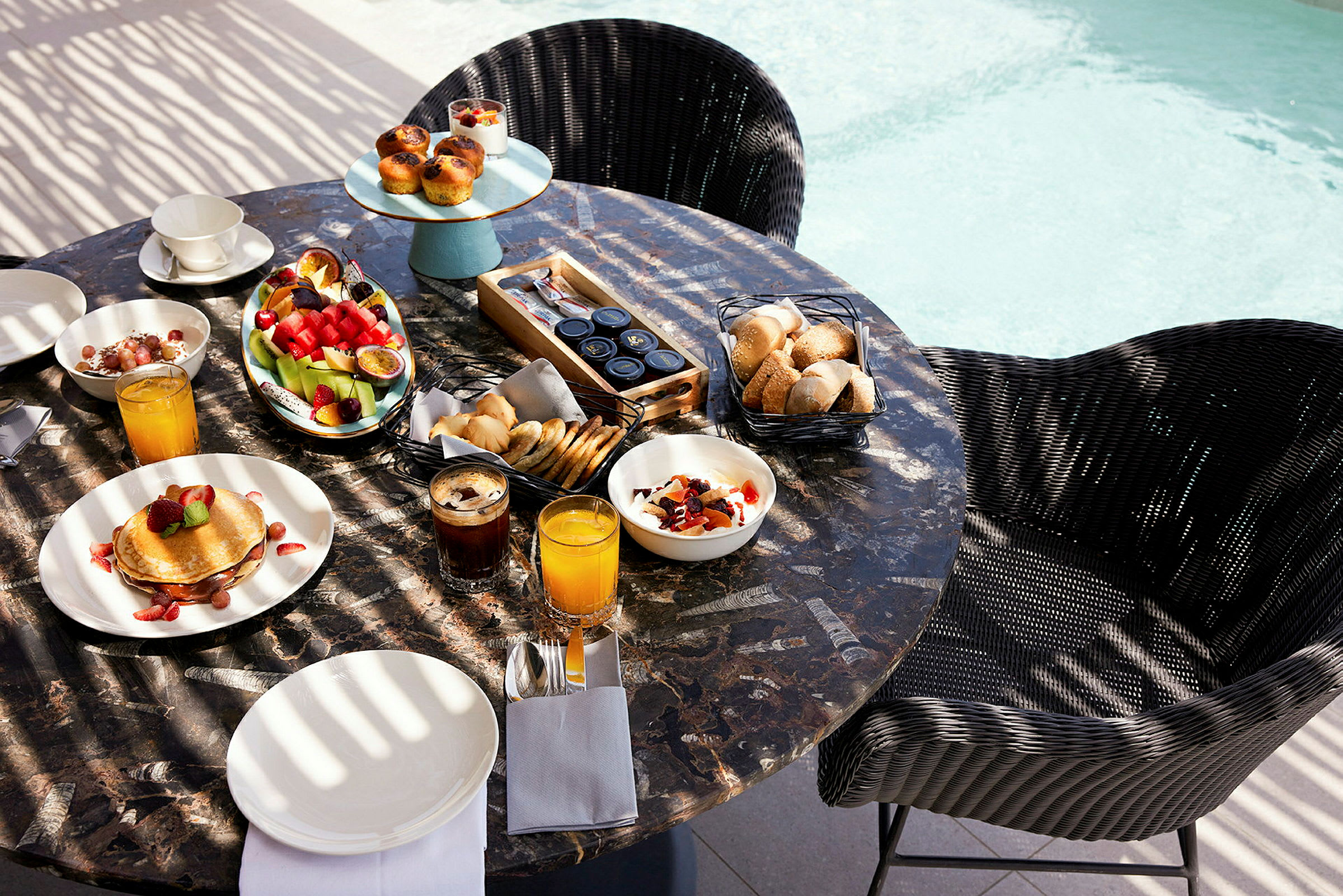 Frokostbord med ulike retter og drikke ved bassengkanten. (AI-generert tekst)