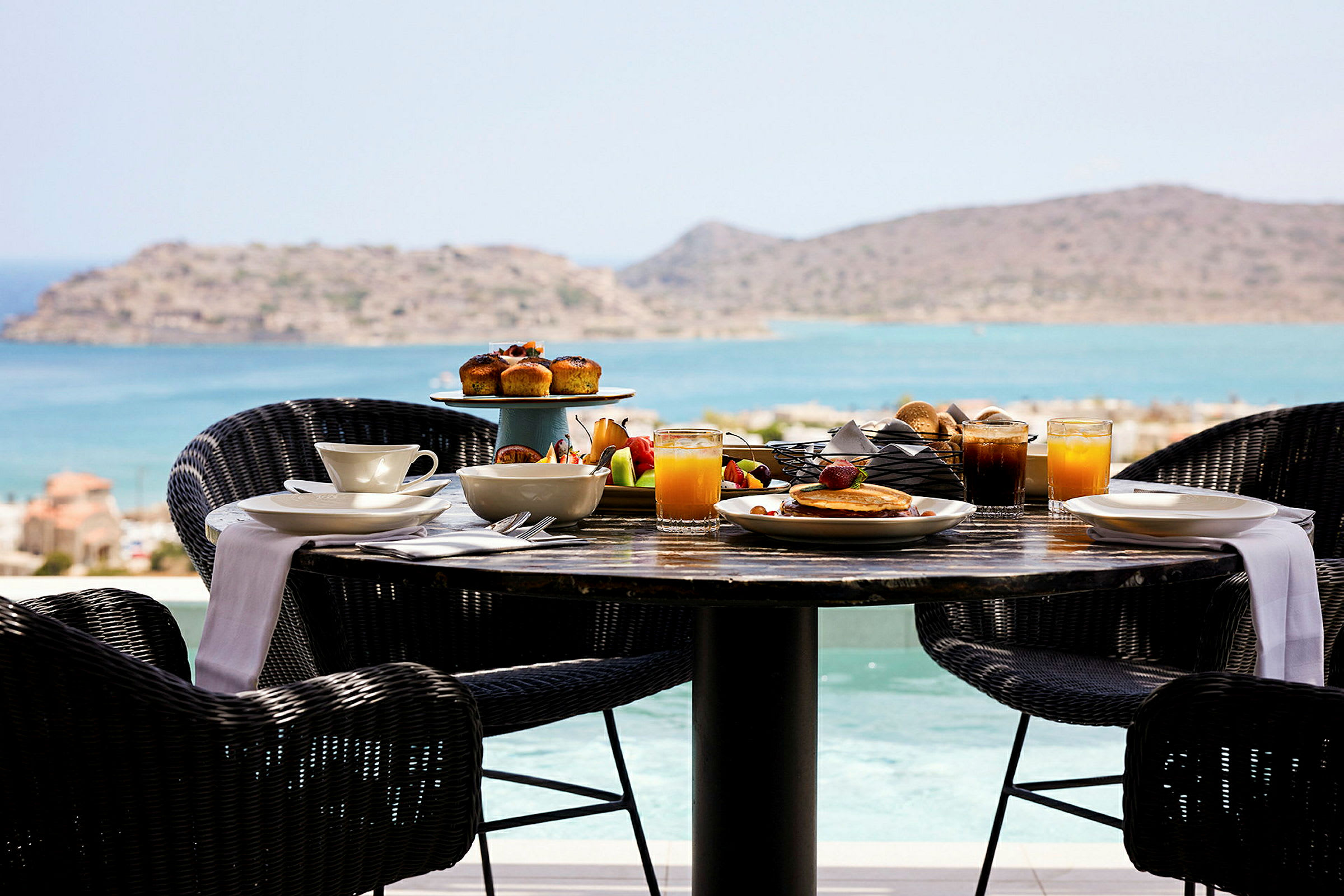 Et frokostbord med mat og drikke med utsikt over havet. (AI-generert tekst)