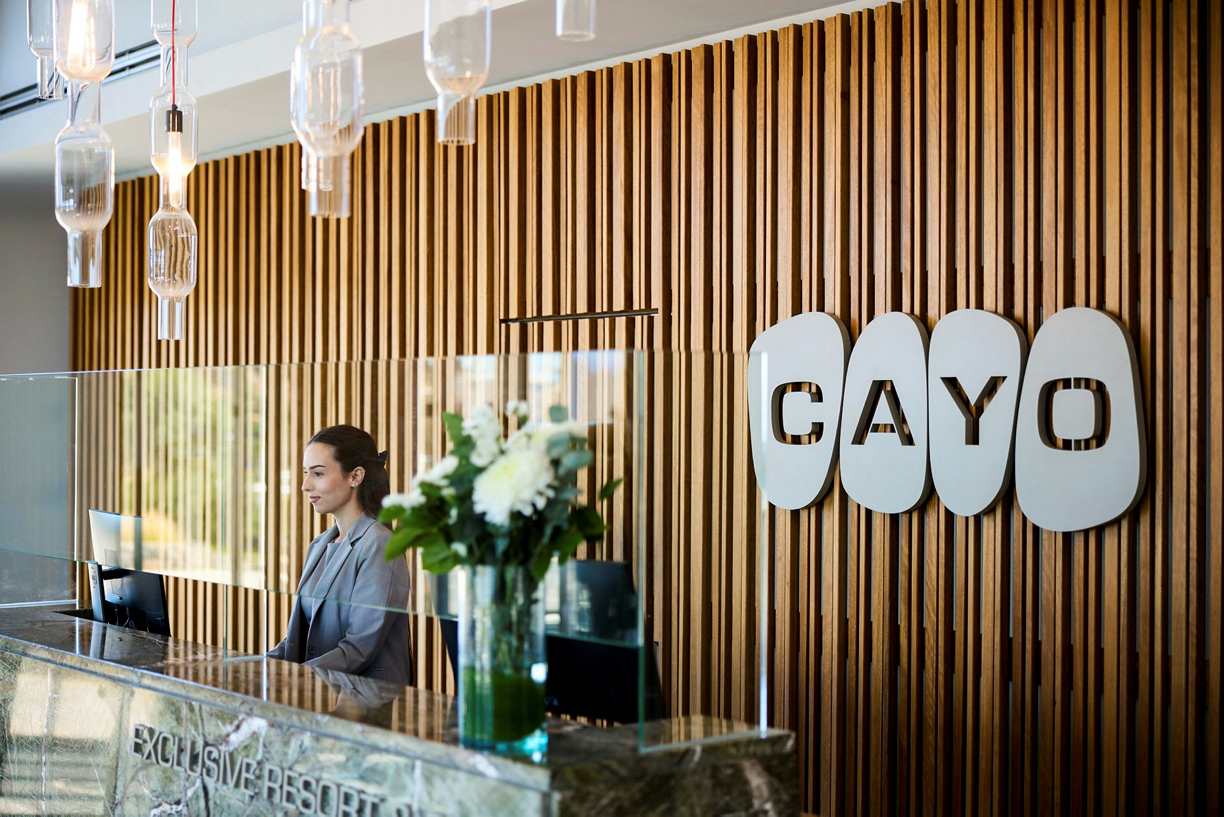 Resepsjon med trepanelvegger og logoen 'Cayo'. (AI-generert tekst)