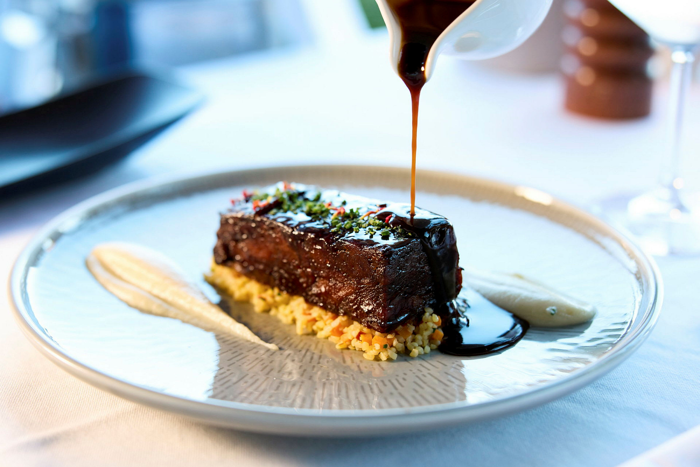 En matrett med kjøtt toppet med saus, servert med puré og tilbehør på en tallerken. (AI-generert tekst)