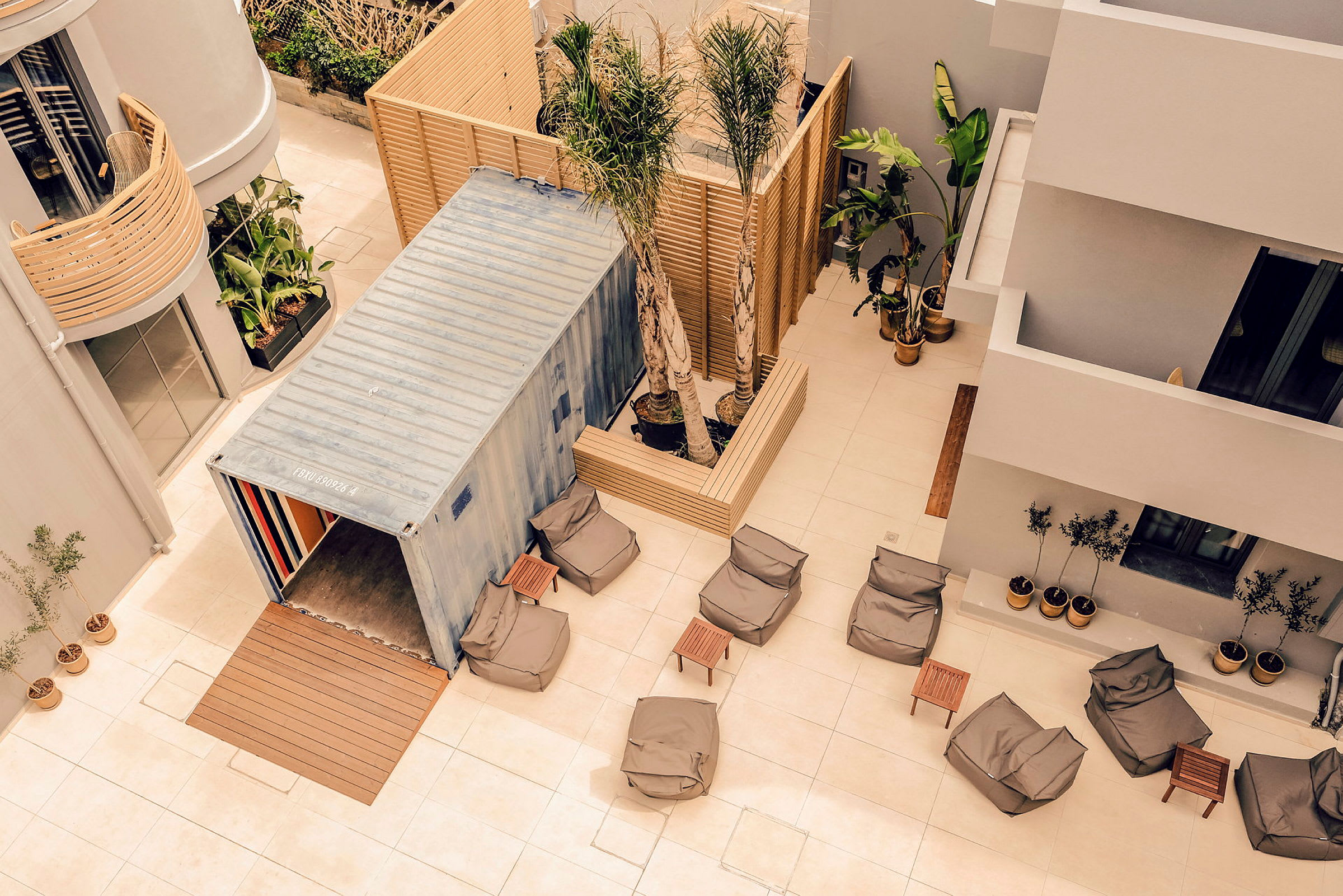 Flere sittesekker og små bord står på en terrasse med moderne møbler og planter. (AI-generert tekst)