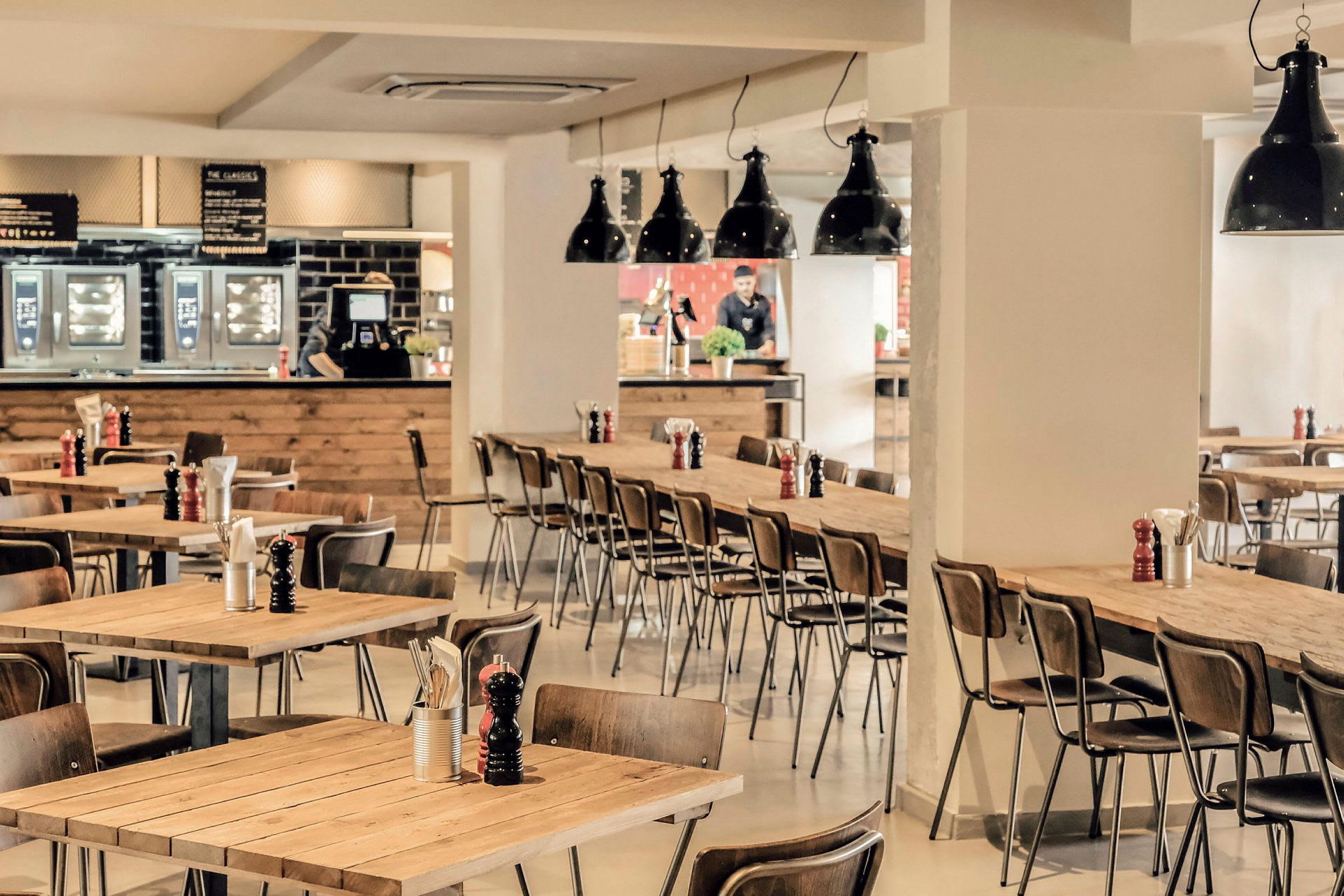 Interiør av en restaurant med trebord og stoler. (AI-generert tekst)