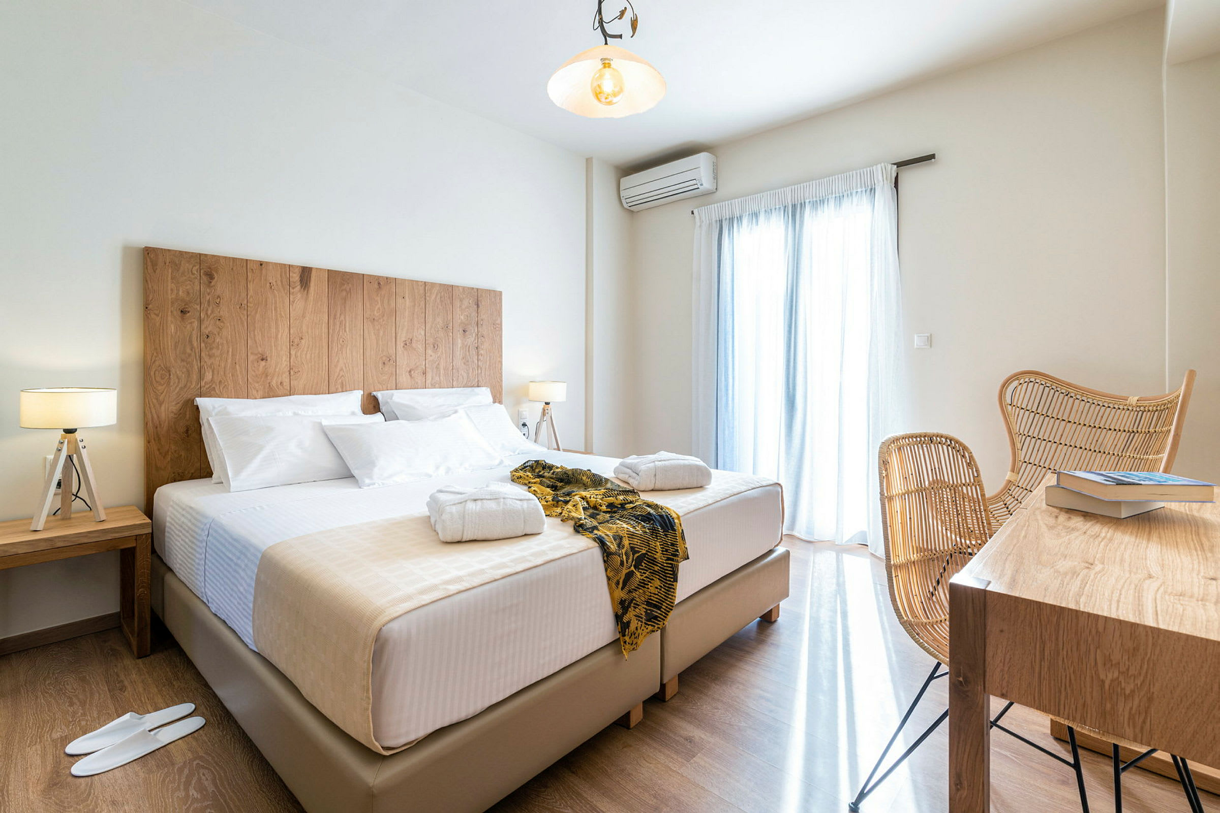Hotellrom med en stor seng, nattbord med lamper, samt en sittegruppe og et bord med bøker. (AI-generert tekst)