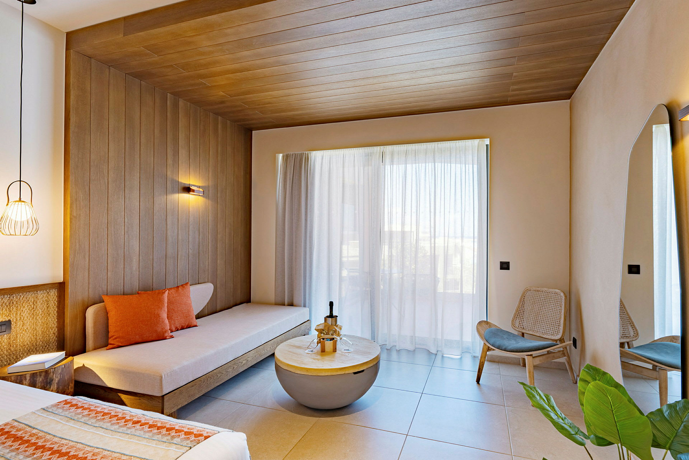 Et moderne hotellrom med sofa, trepaneler, store glassvinduer og stilig interiør. (AI-generert tekst)