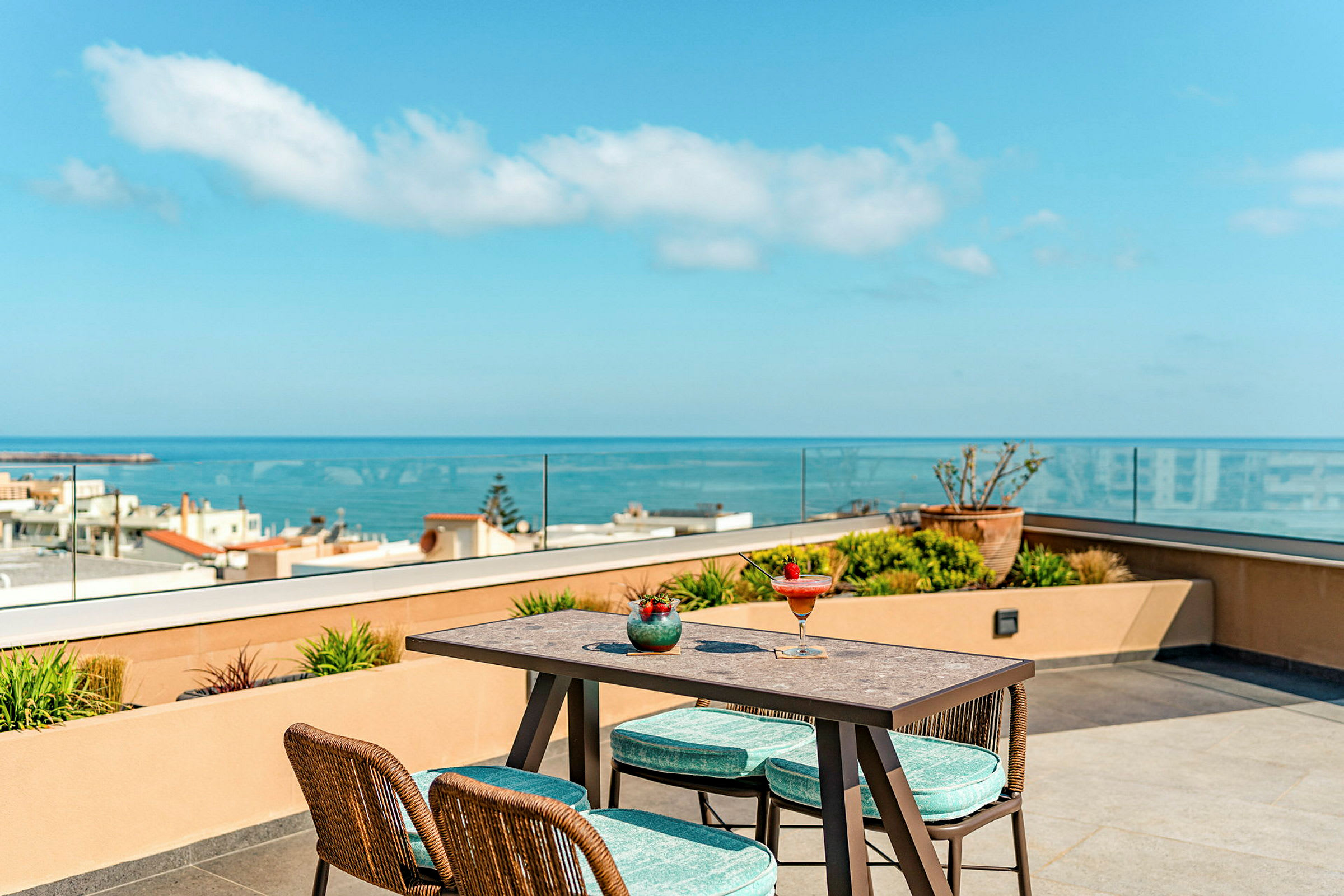 Et bord og stoler på en terrasse med utsikt over havet. (AI-generert tekst)