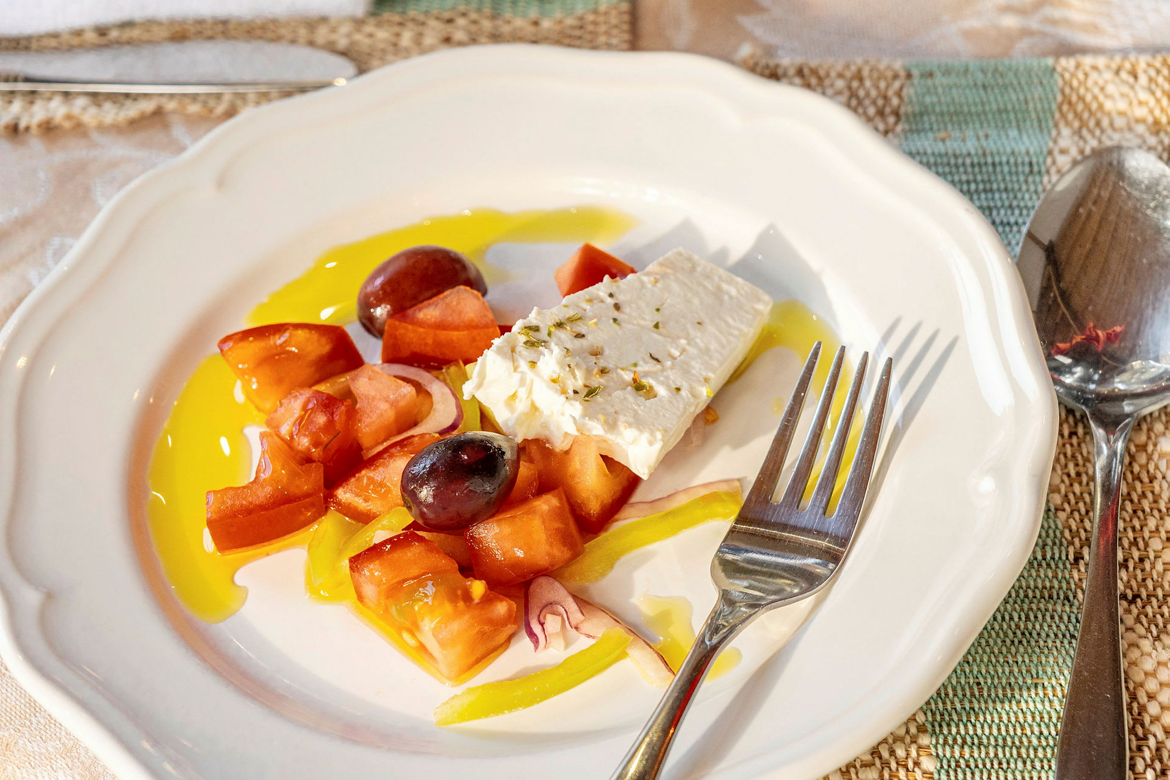 En tallerken med gresk salat som inneholder tomater, fetaost, oliven og paprika. (AI-generert tekst)