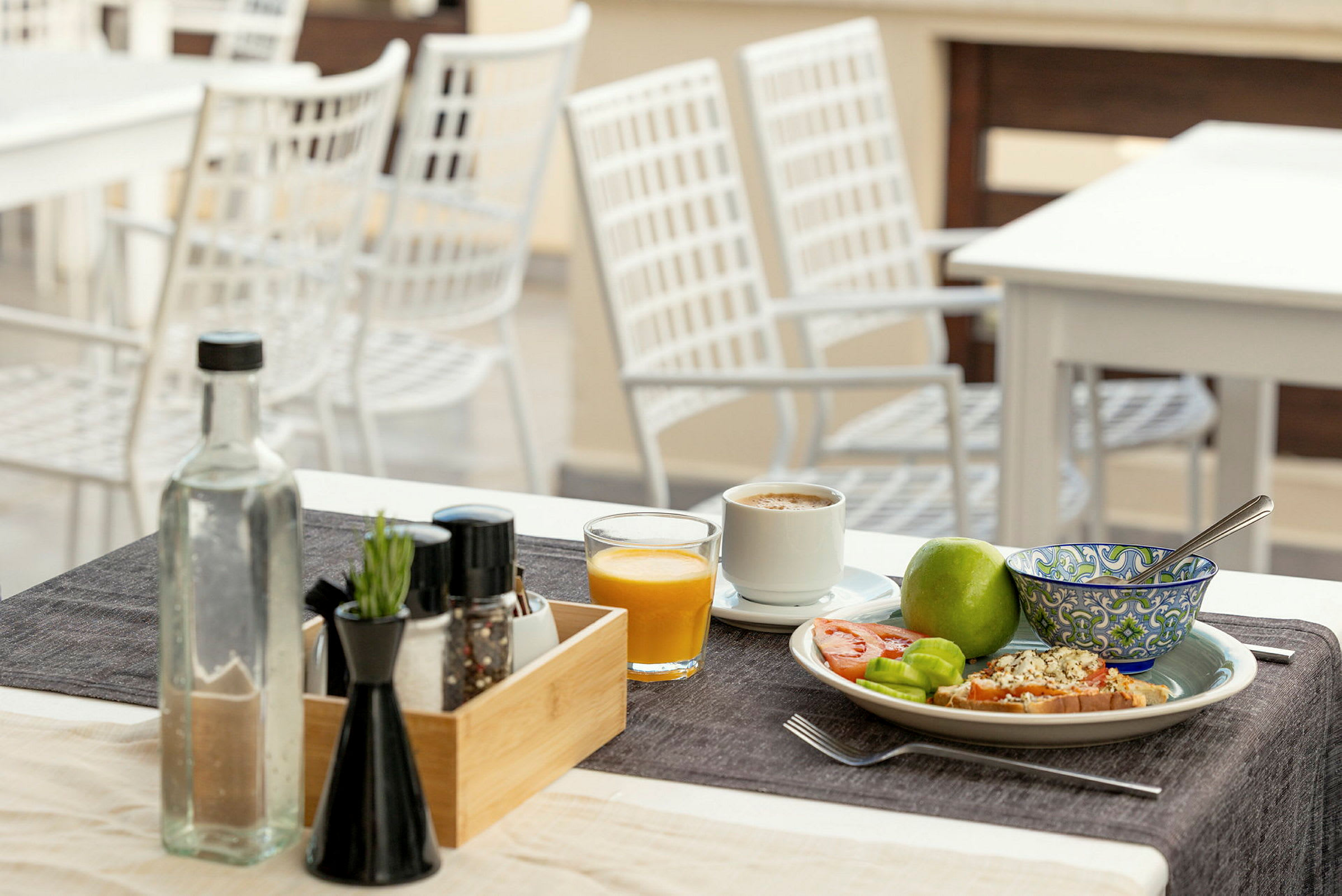Et dekket bord med frokost: kaffe, juice, frukt og brød. (AI-generert tekst)