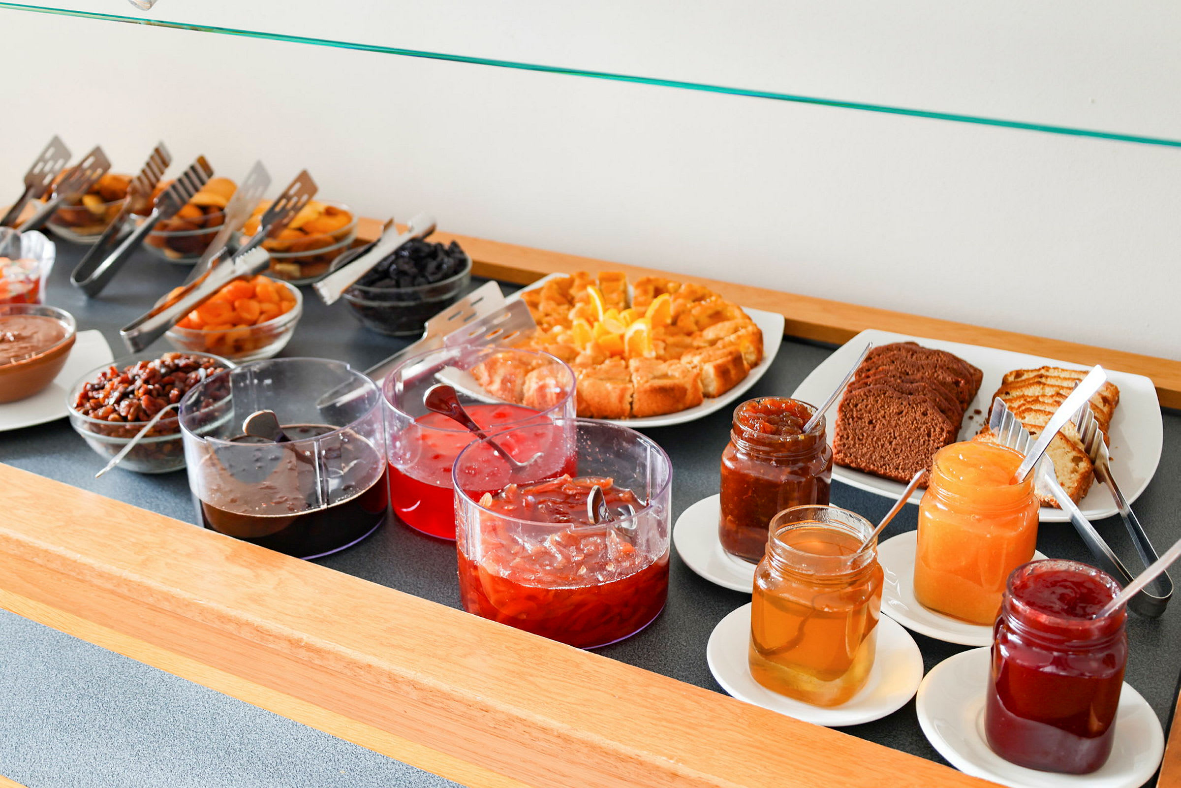Buffet med forskjellige syltetøy, bakverk og tørket frukt. (AI-generert tekst)