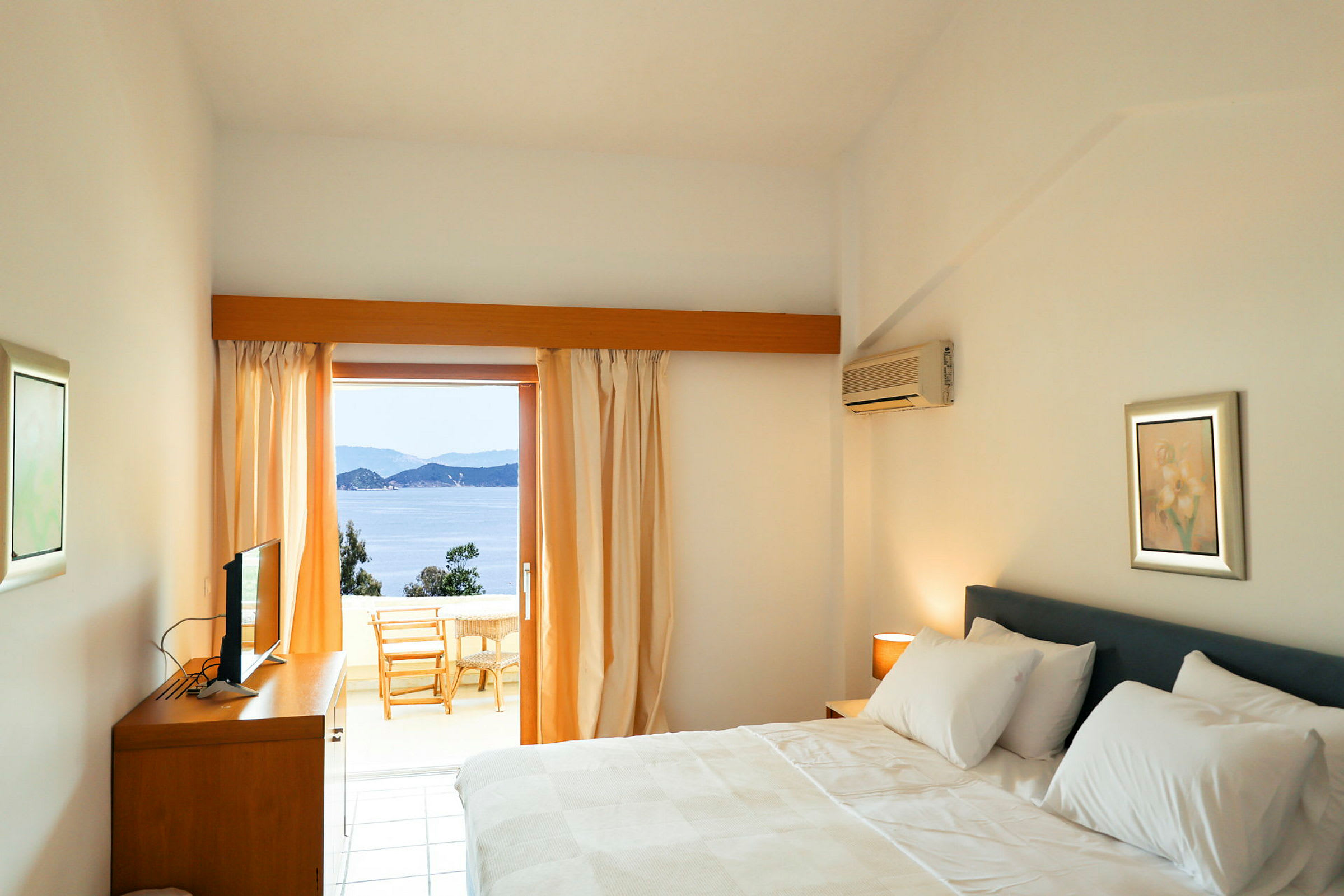 Hotellrom med en dobbeltseng og utsikt over sjøen fra en balkong. (AI-generert tekst)