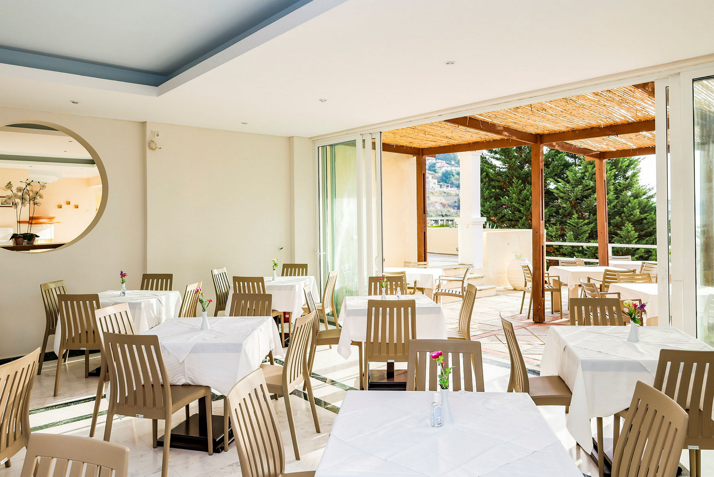 Restaurant med spisebord og stoler, utsikt mot en terrasse. (AI-generert tekst)