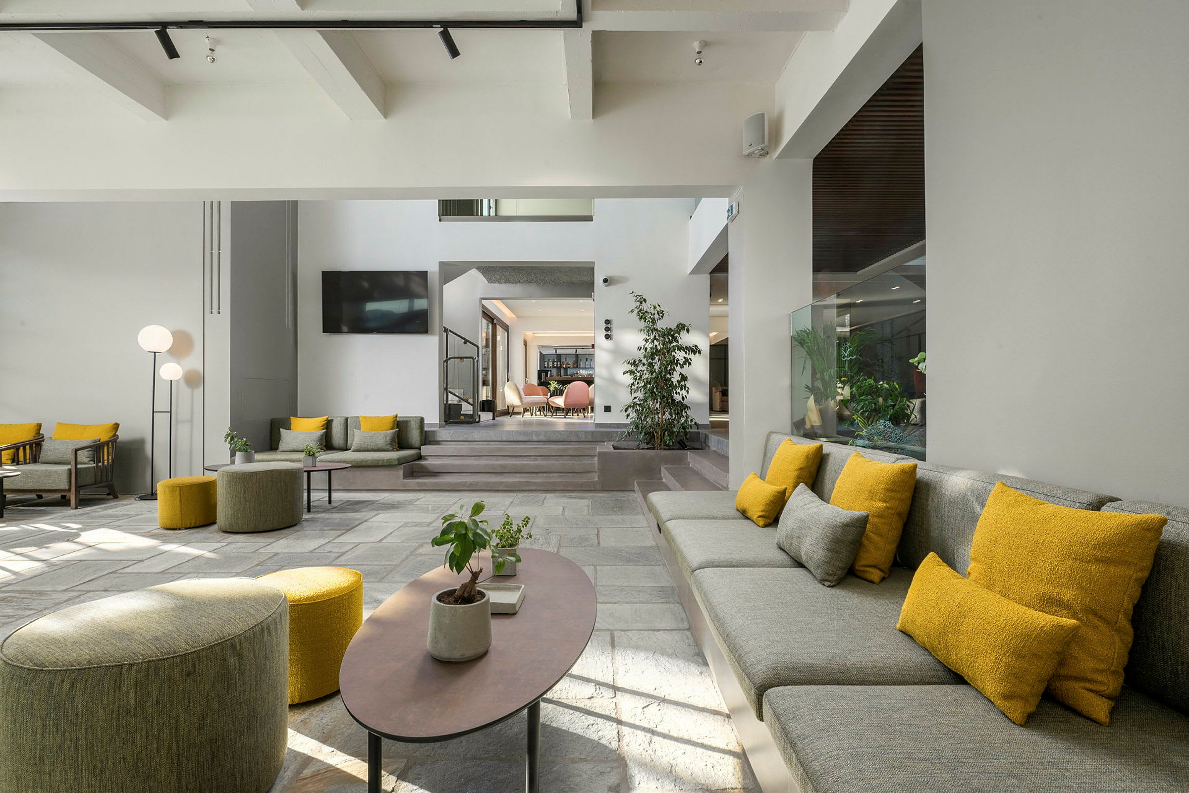 En moderne hotellobby med sittemøbler i grått og gult. (AI-generert tekst)