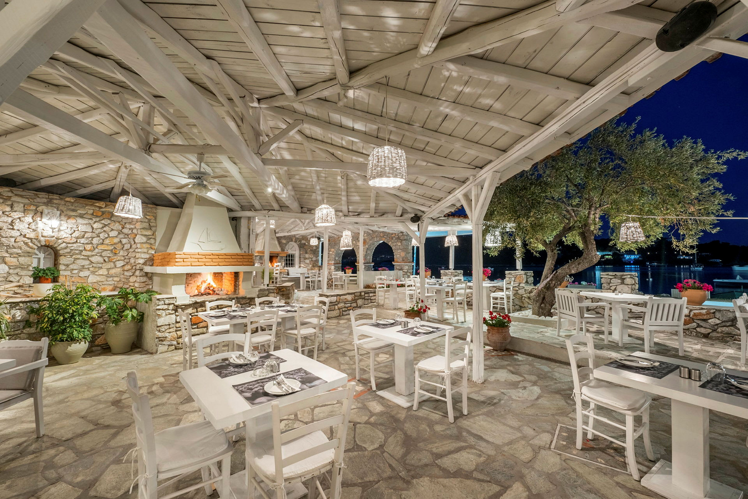 Utendørs restaurant med hvite møbler og steinbekledd interiør. (AI-generert tekst)