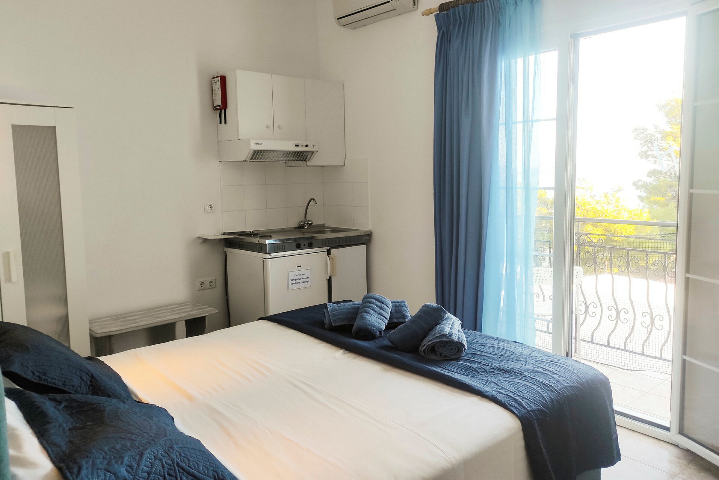Hotellrom med seng, kjøkkenområde og balkong med utsikt. (AI-generert tekst)