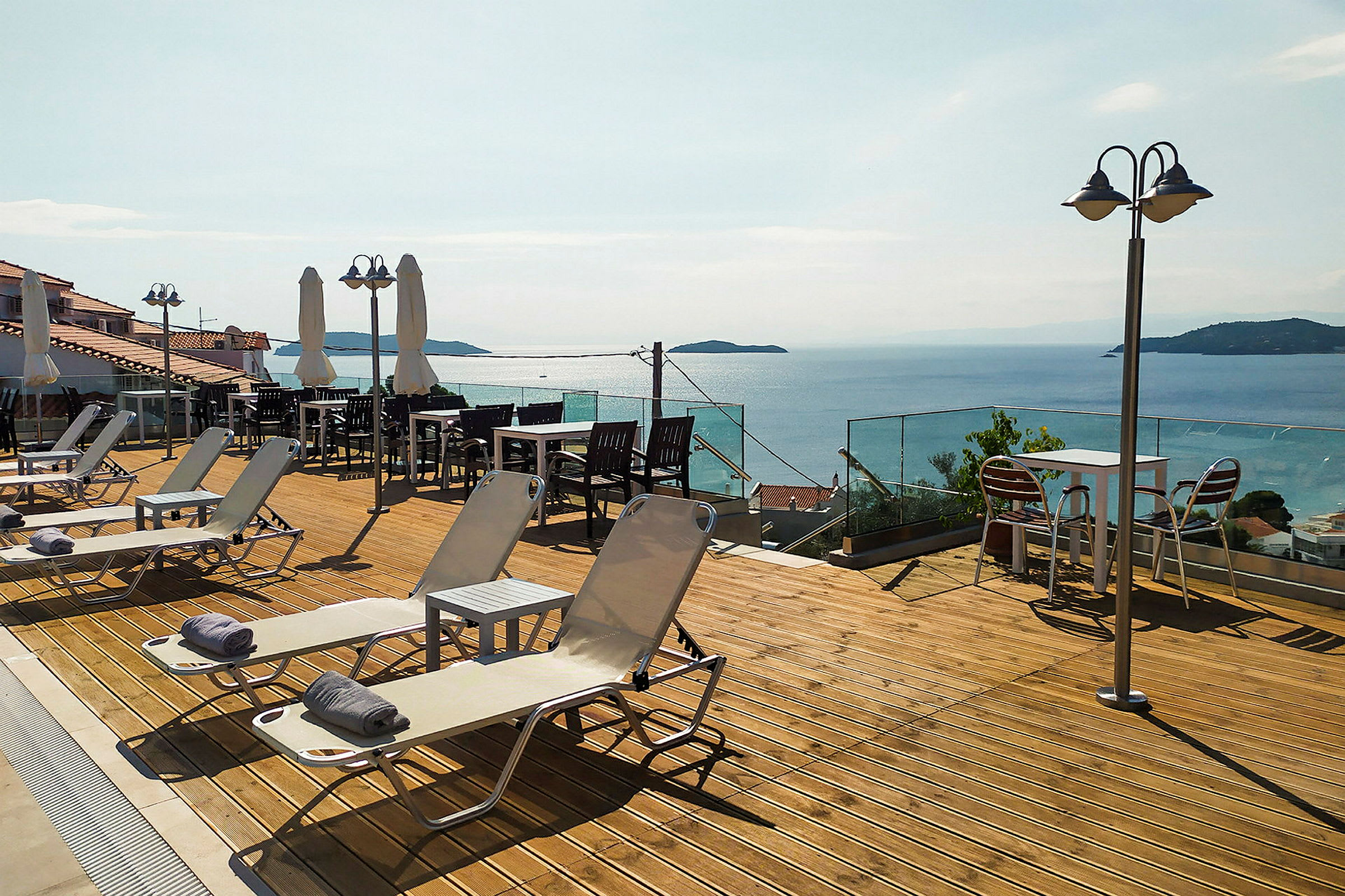 En terrasse med solsenger, bord og stoler samt utsikt over havet. (AI-generert tekst)