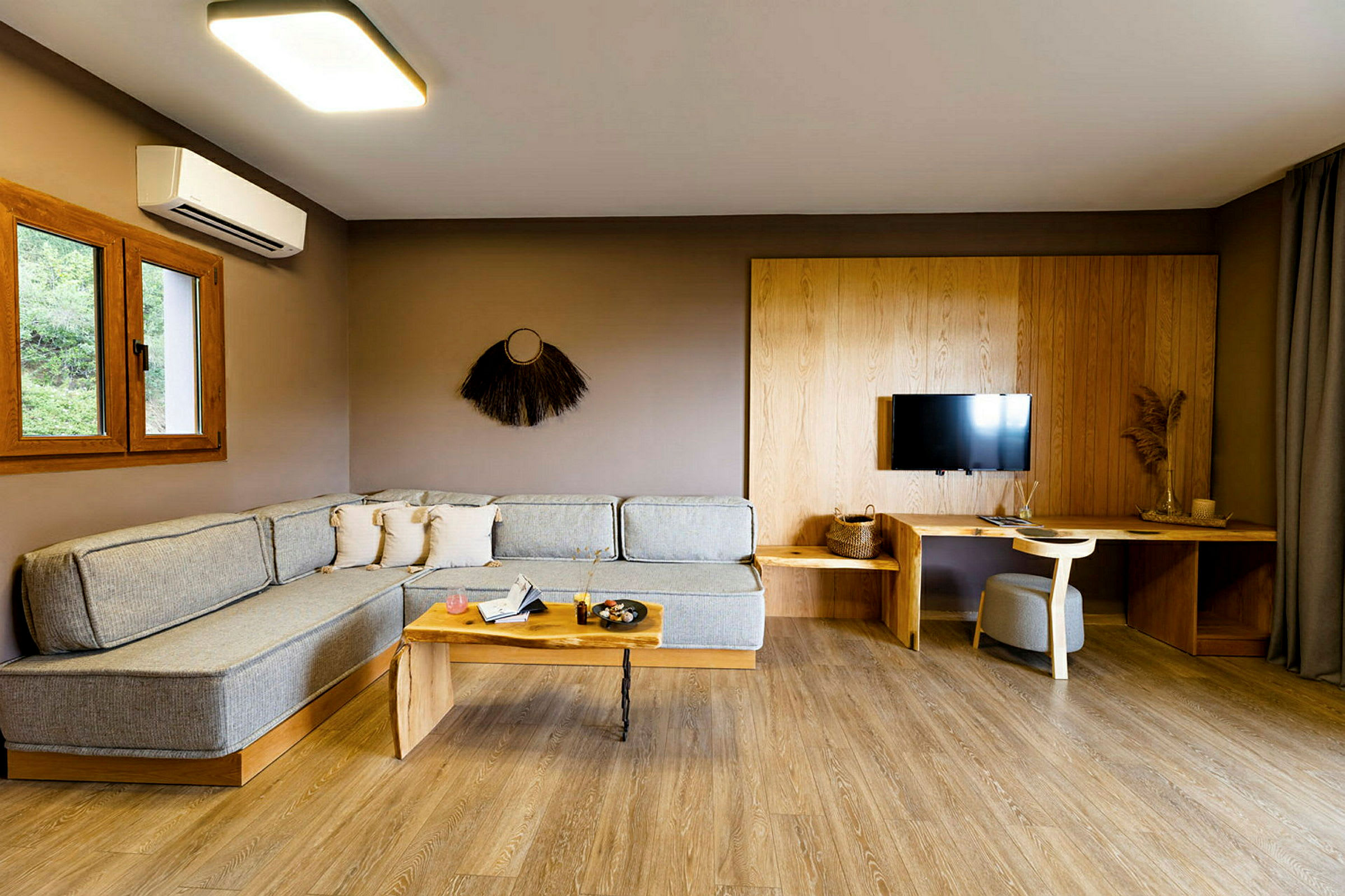 Moderne stue med hjørnesofa, sofabord, TV på veggen og skrivebord med stol. (AI-generert tekst)