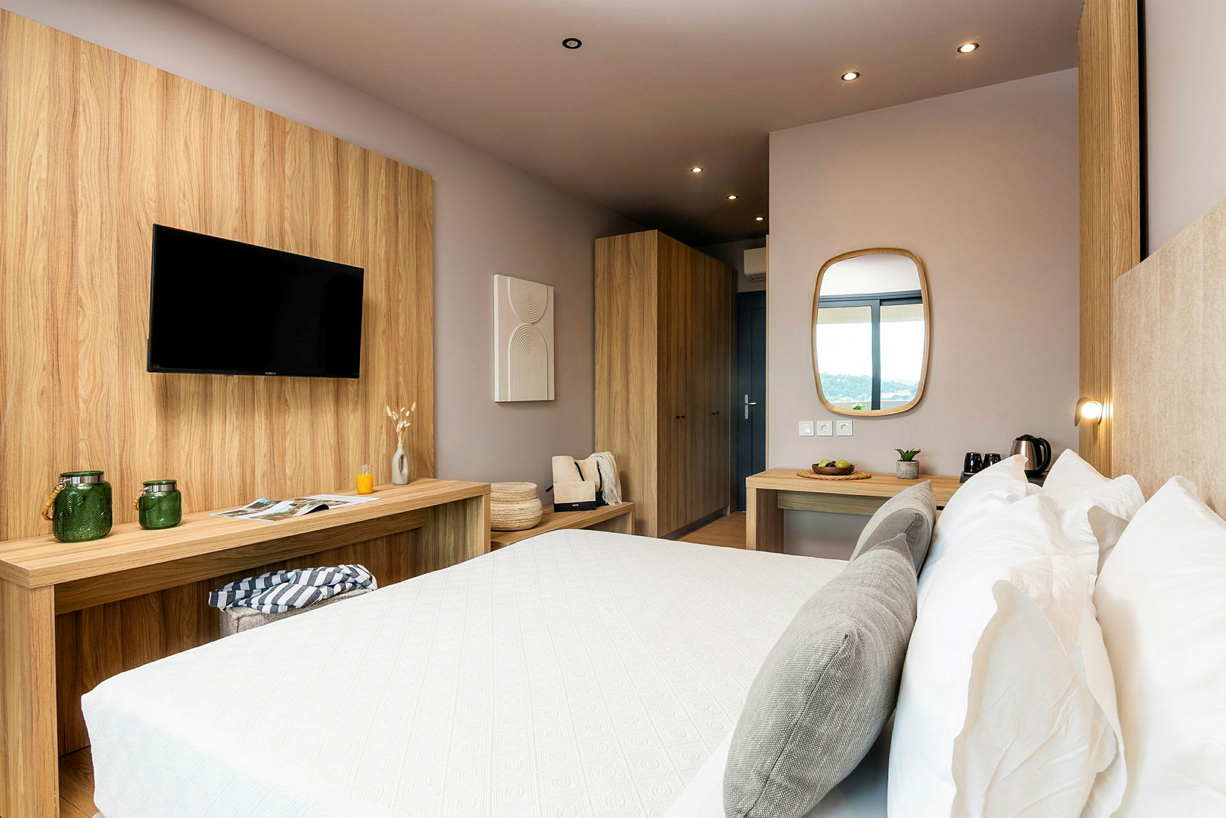 Et moderne hotellrom med en dobbeltseng, treinteriør, bord med speil og TV. (AI-generert tekst)