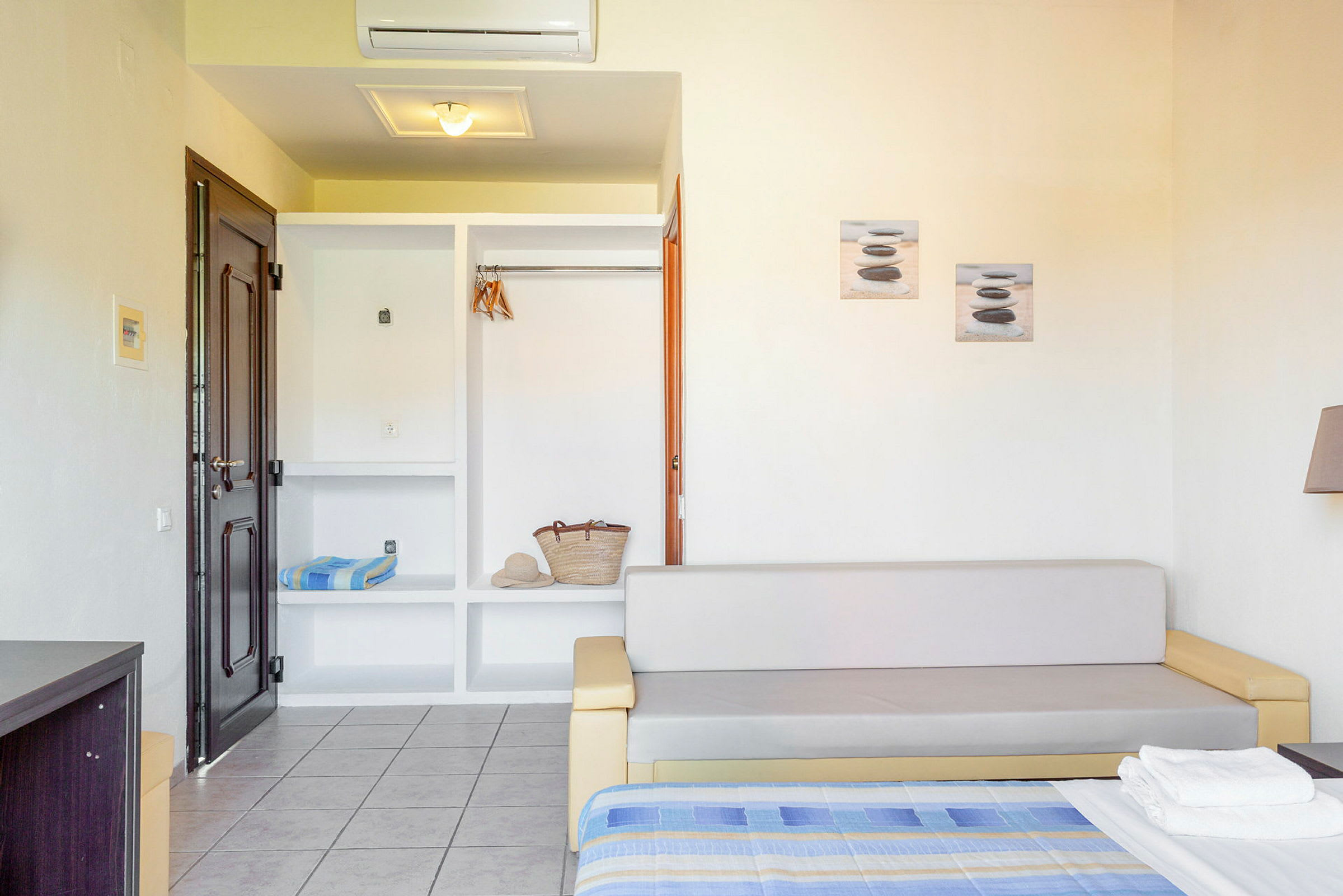 Et hotellrom med sofa, åpen garderobe og seng. (AI-generert tekst)