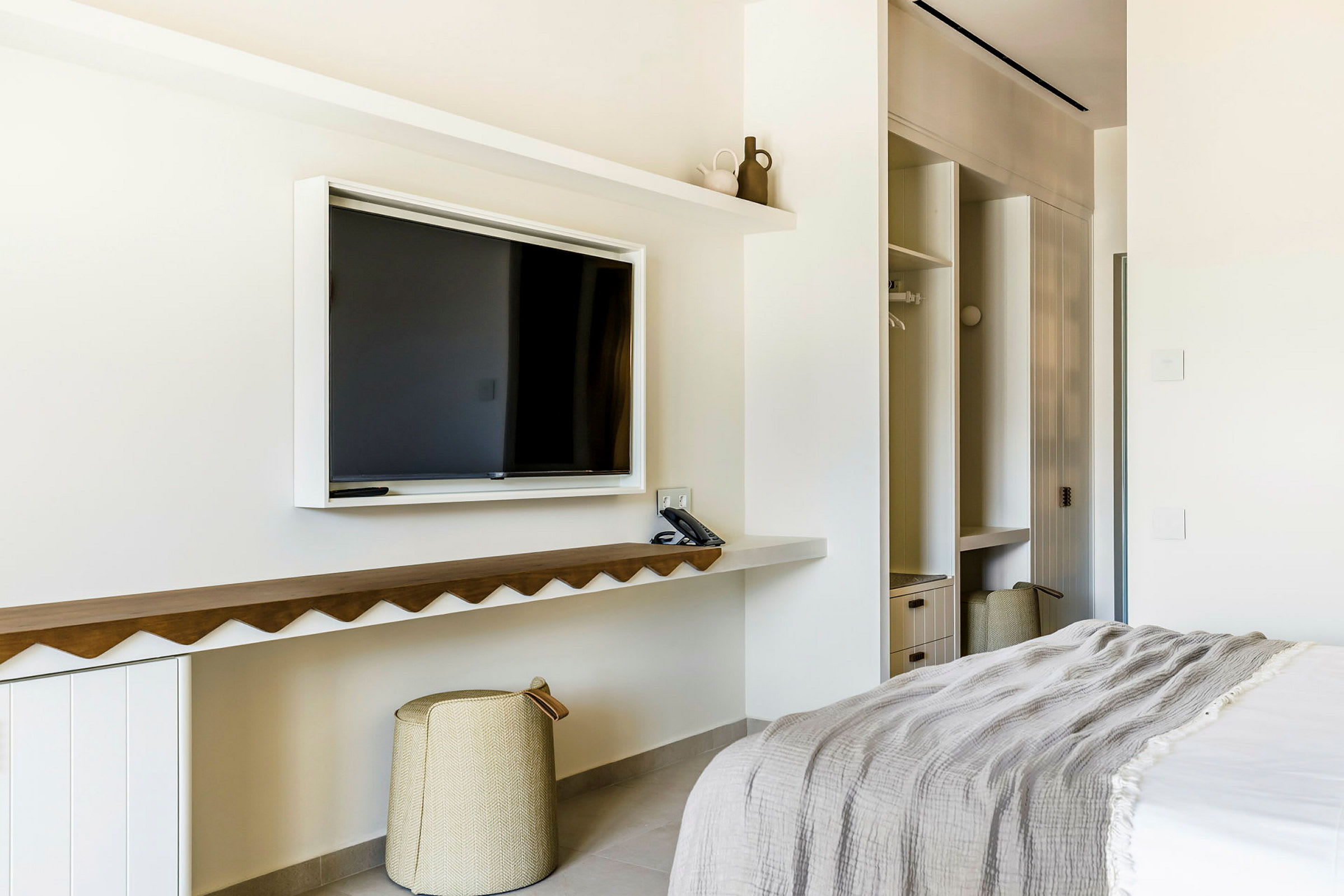 Hotellrom med TV, seng og oppbevaringsplass. (AI-generert tekst)
