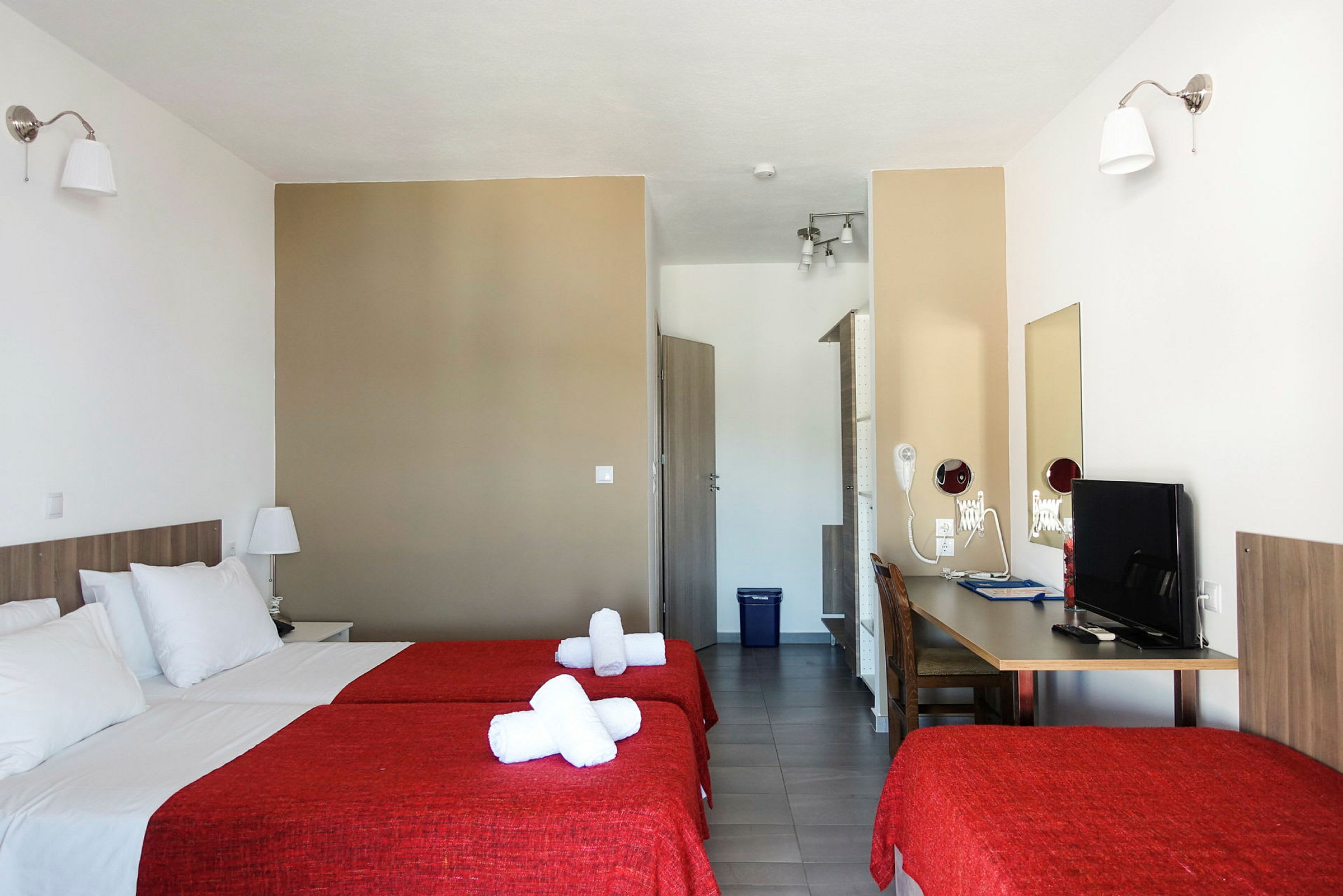 Hotellrom med to senger og røde sengetepper. (AI-generert tekst)