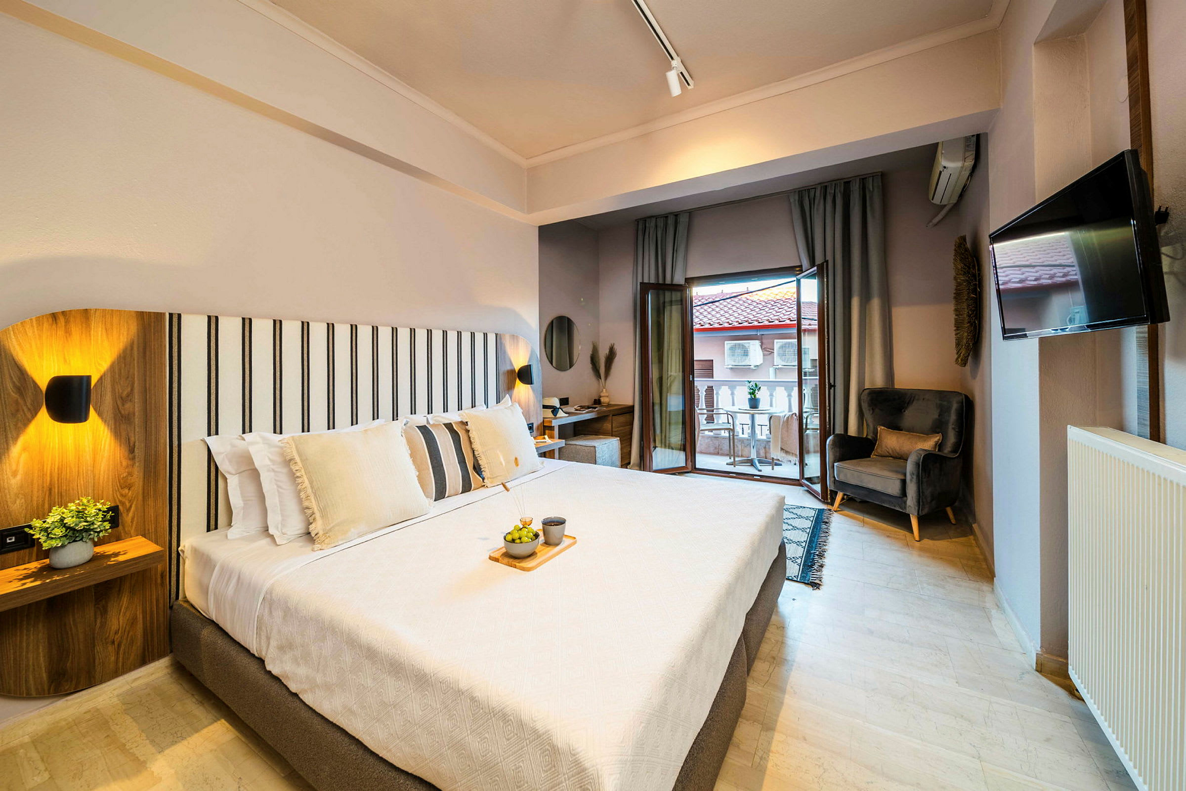 Et lyst og moderne hotellrom med en stor seng, sitteplass og balkong. (AI-generert tekst)