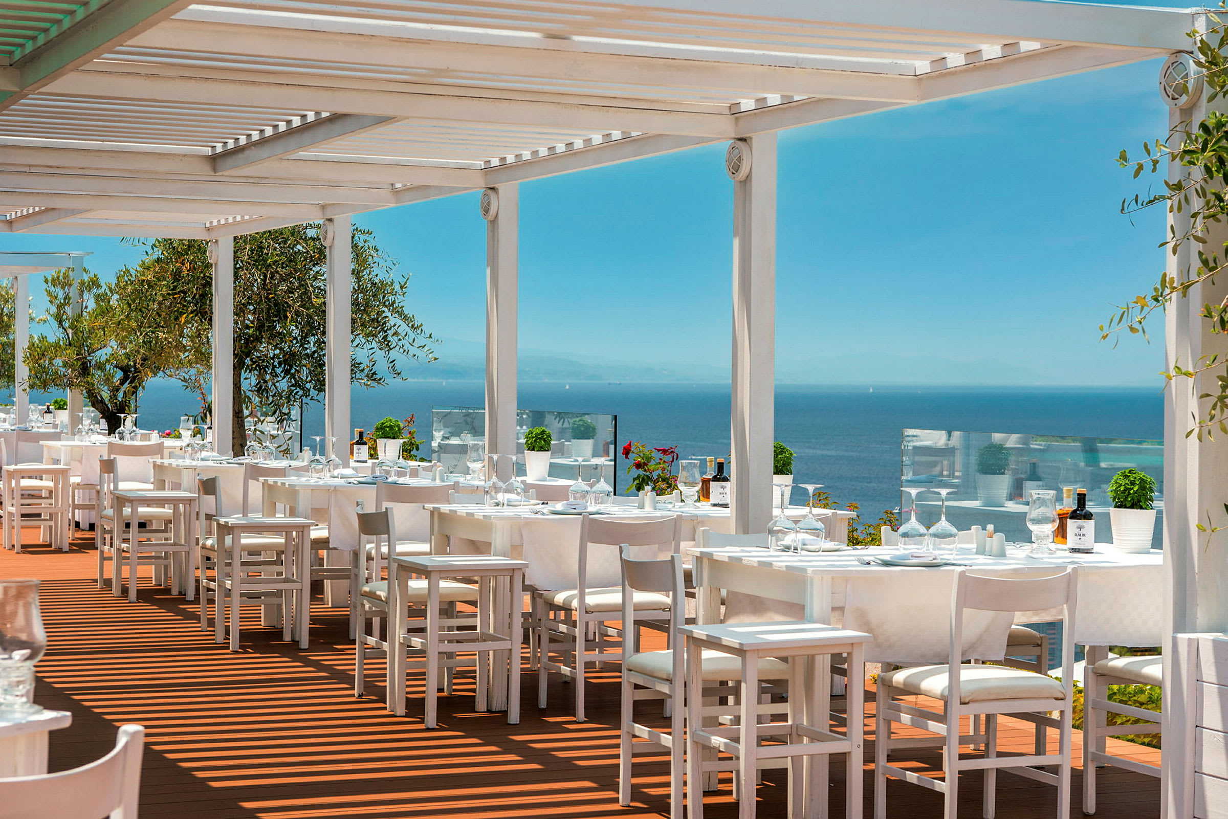 Utendørsrestaurant med hvite møbler og utsikt over havet. (AI-generert tekst)