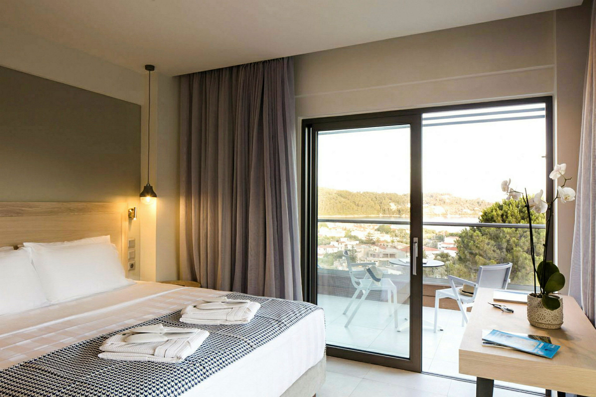 Hotellrom med dobbeltseng, balkong og utsikt over grøntområder. (AI-generert tekst)