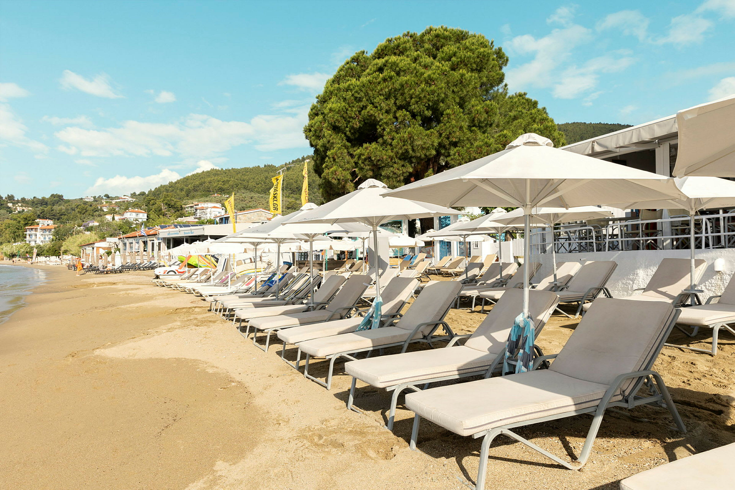 Solstoler og parasoller ved en sandstrand. (AI-generert tekst)