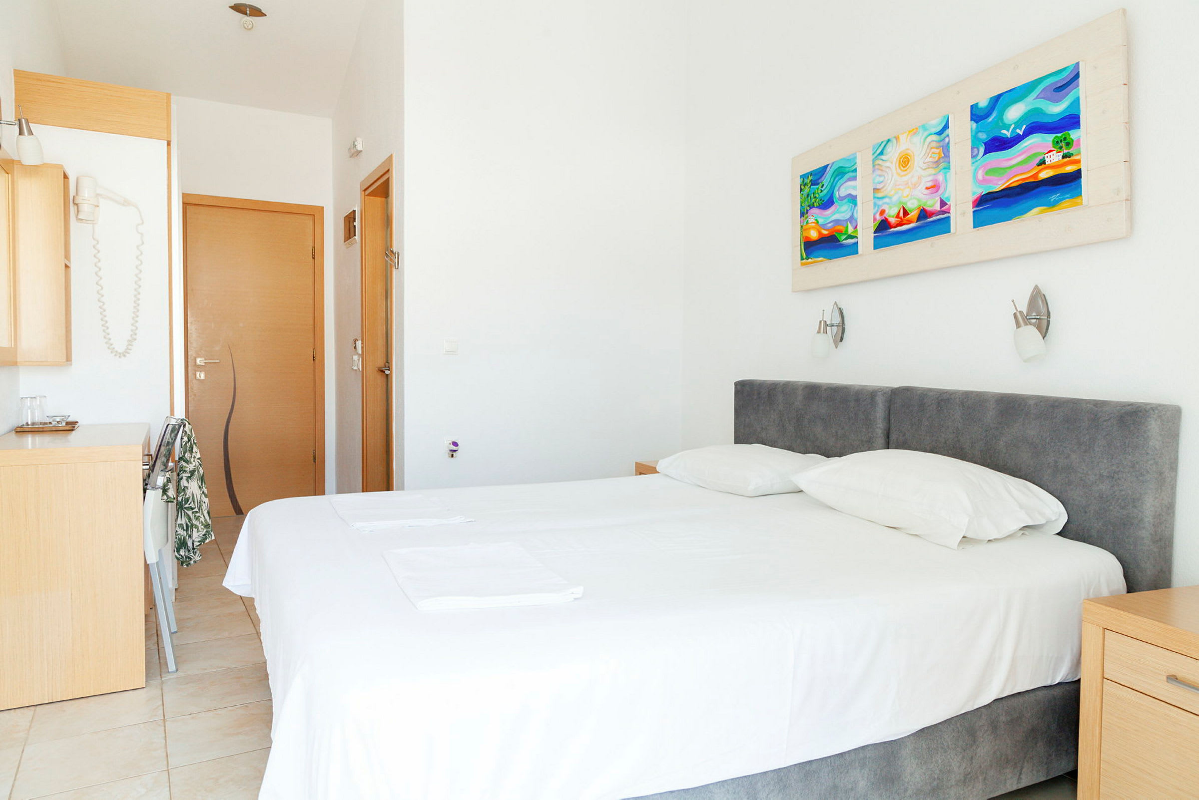 Et hotellrom med en seng, to puter og dekorasjoner på veggen. (AI-generert tekst)