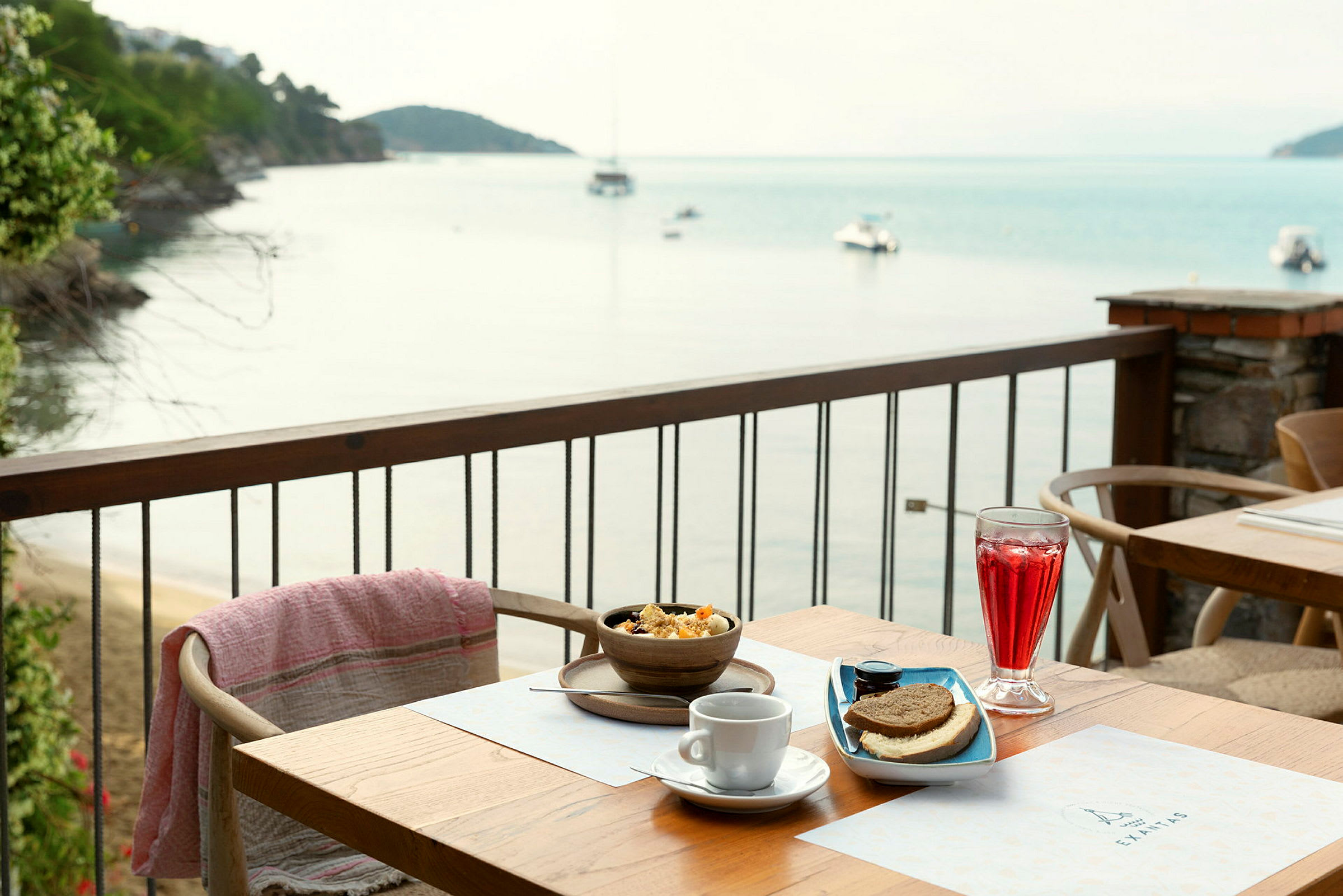 Frokost servert på en terrasse med utsikt over havet og båter. (AI-generert tekst)