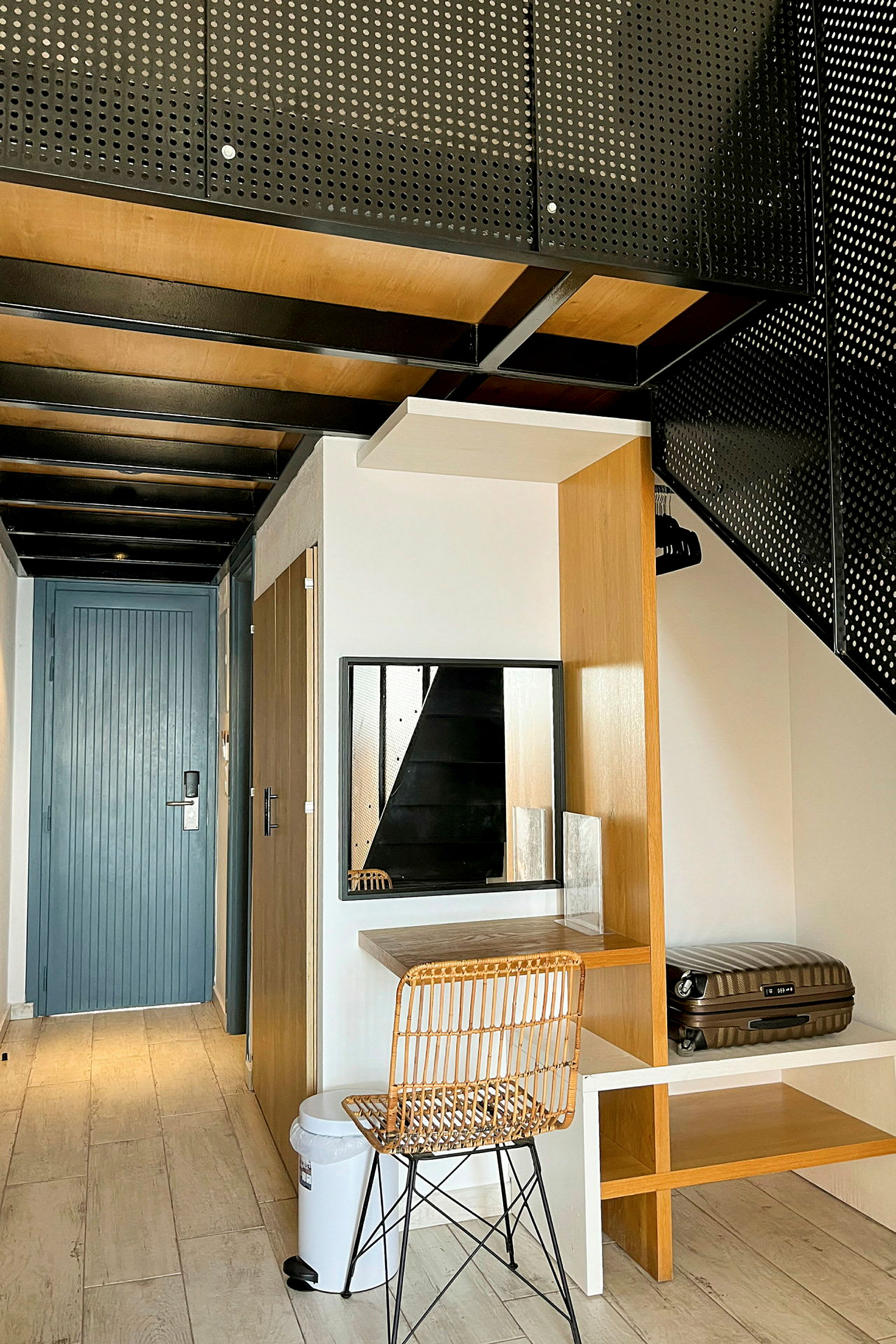 Moderne hotellrom med tredetaljer, stol og bord, samt en koffert plassert i en hylle. (AI-generert tekst)