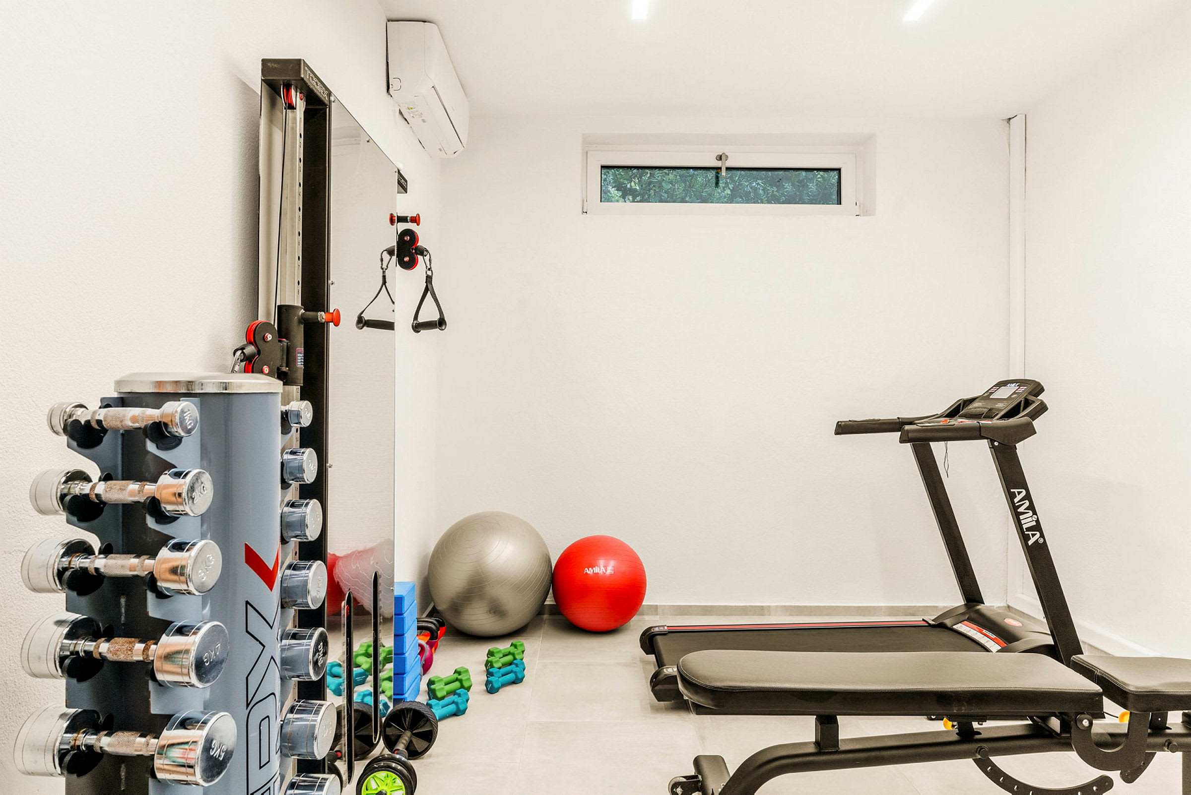 Et treningsrom med utstyr som håndvekter, yogaballer og en tredemølle. (AI-generert tekst)