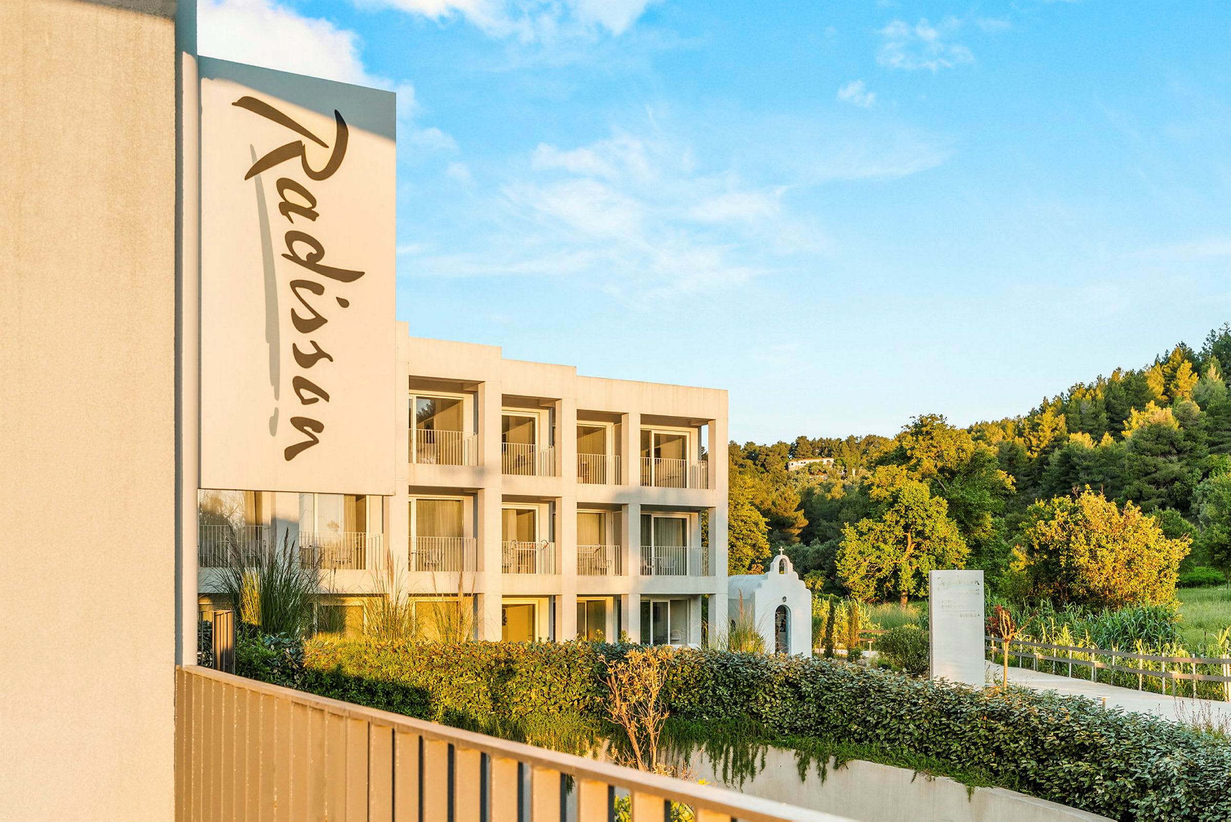 Bilde av en bygning med Radisson-logoen og omgivende grøntområder. (AI-generert tekst)