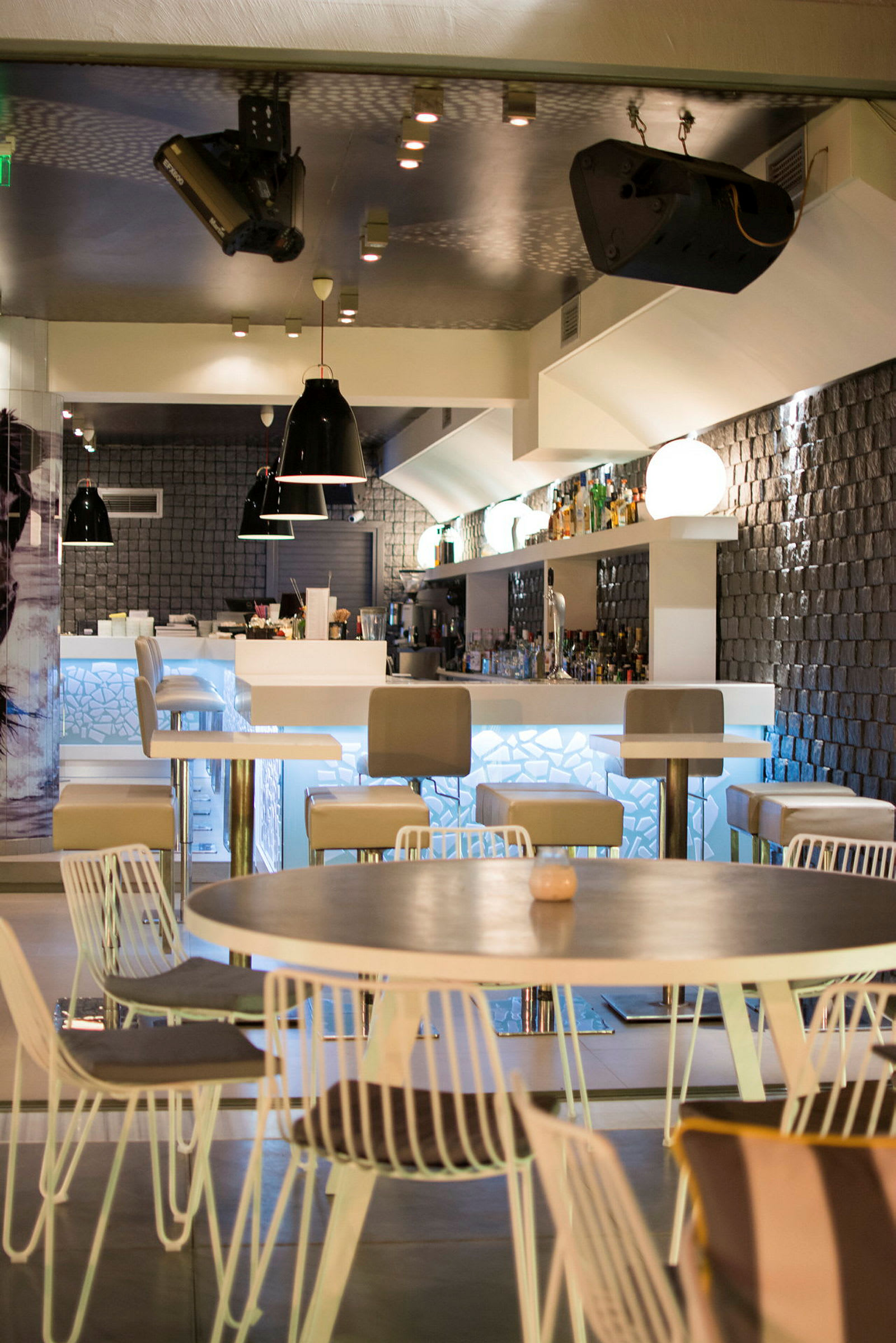 En moderne bar med høye stoler, bord og et belyst serveringsområde. (AI-generert tekst)