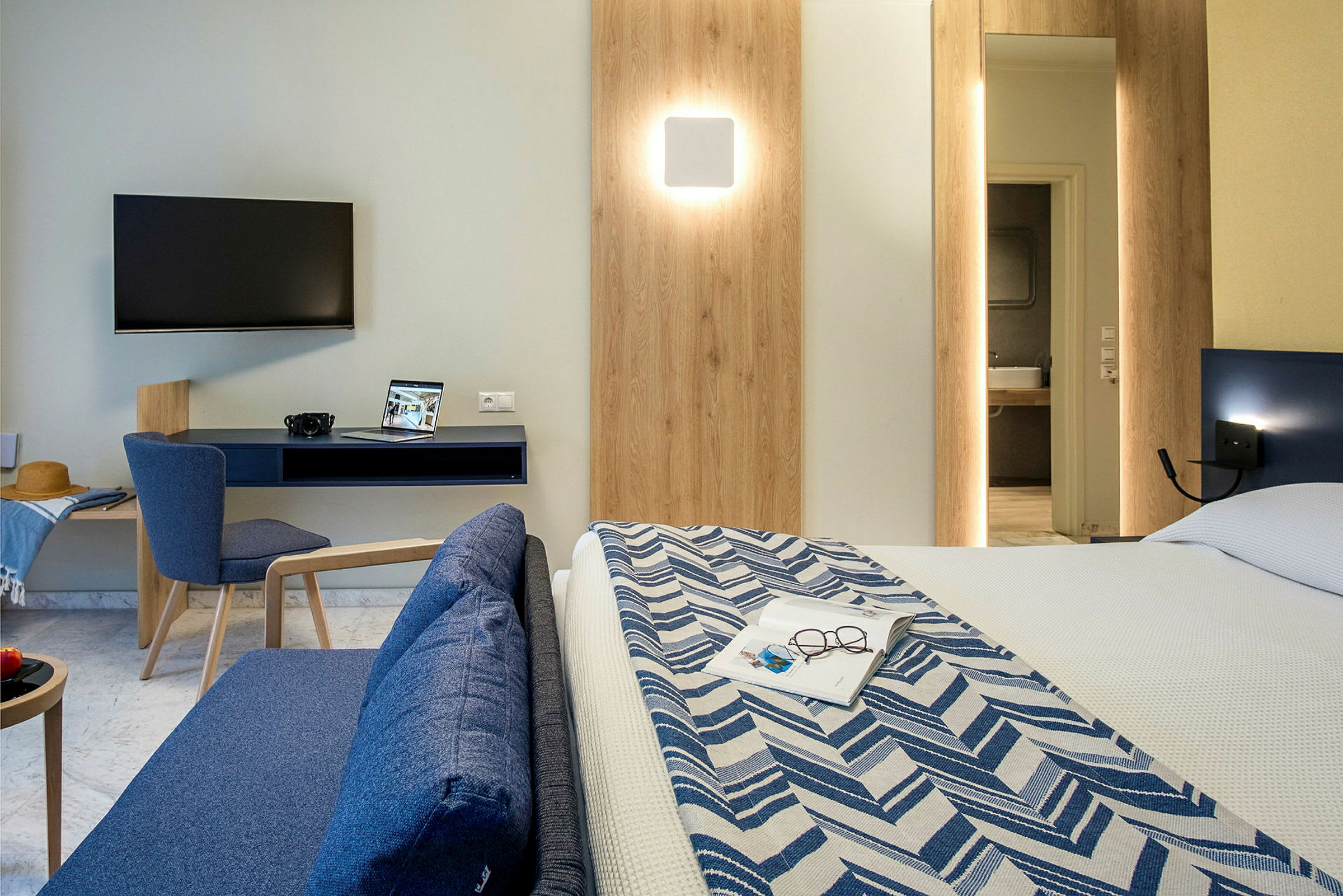 Moderne hotellrom med TV, skrivebord, sofa og seng. (AI-generert tekst)