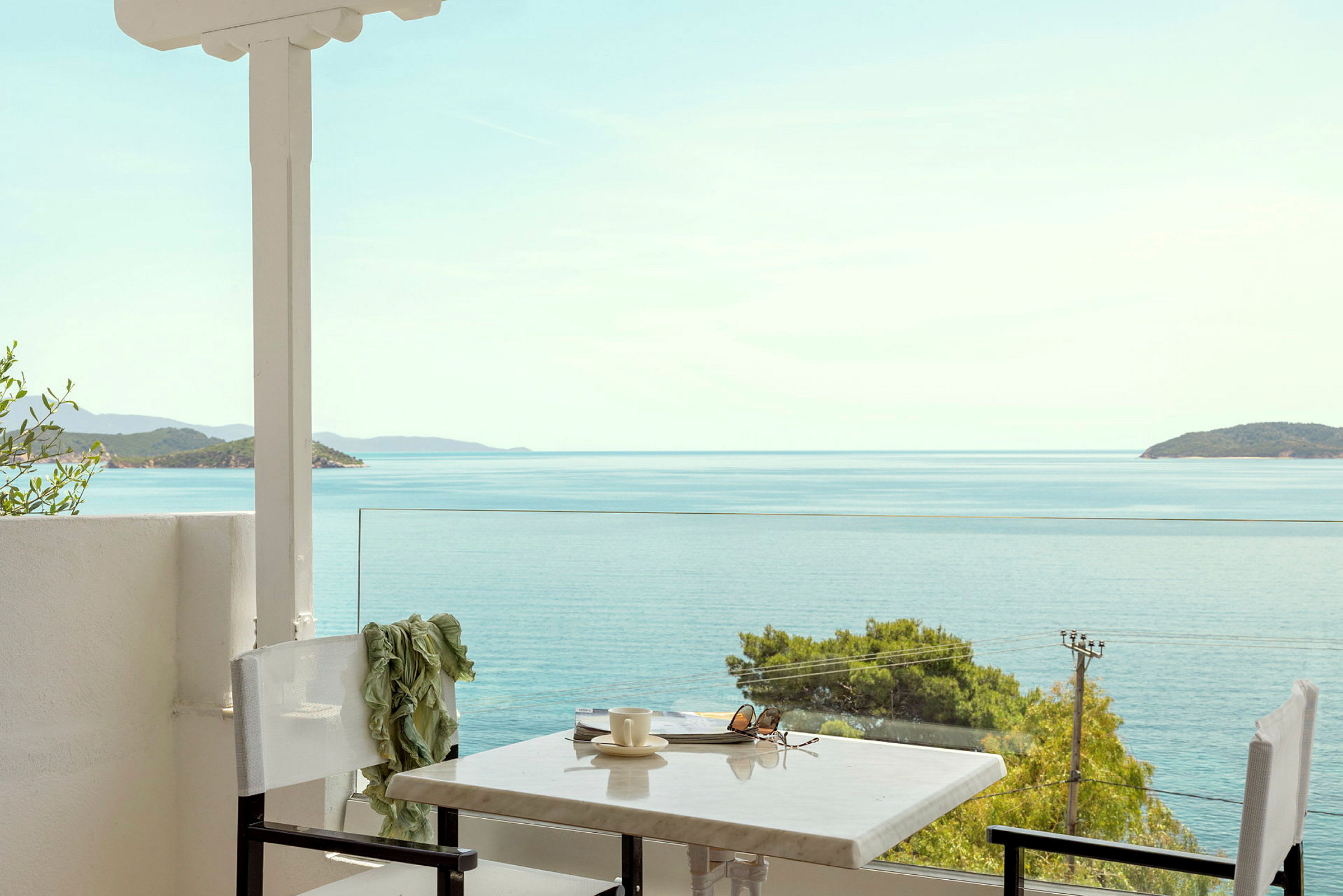 Utsikt mot havet fra en terrasse med bord og stoler. (AI-generert tekst)