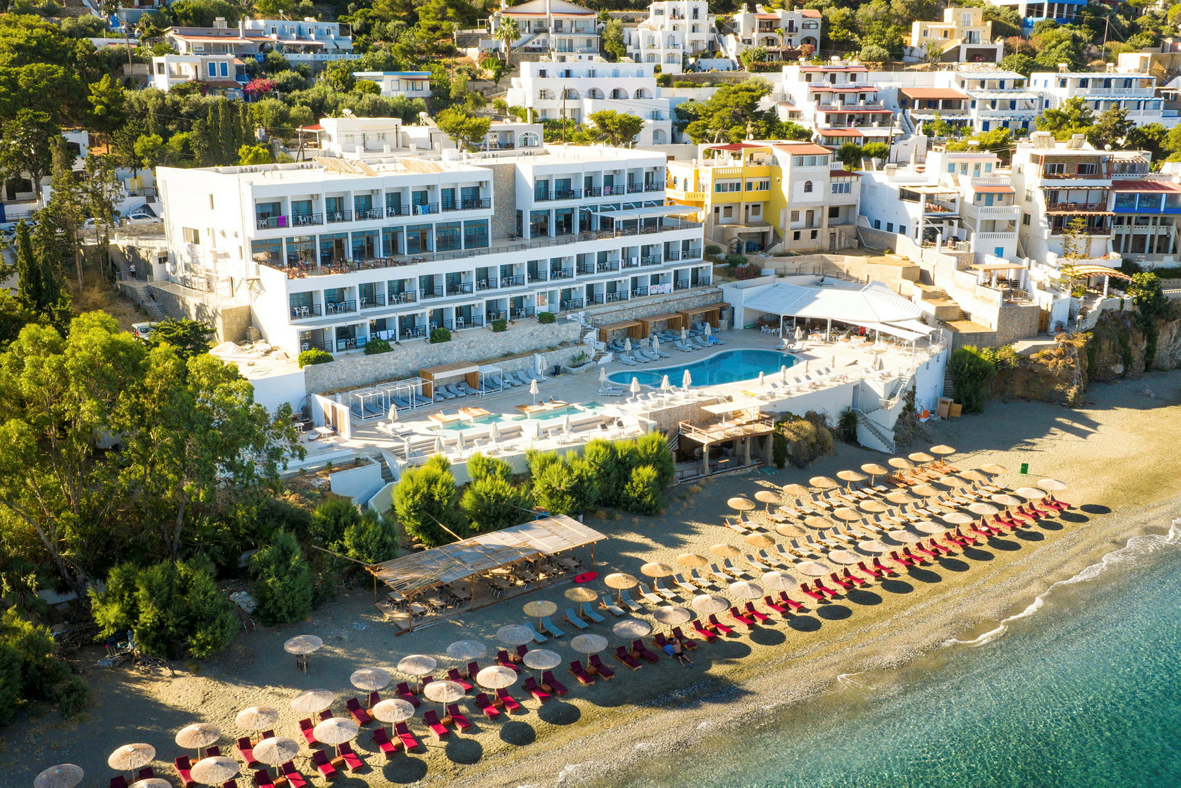Hotellkompleks med bassengområde og solsenger på en sandstrand. (AI-generert tekst)