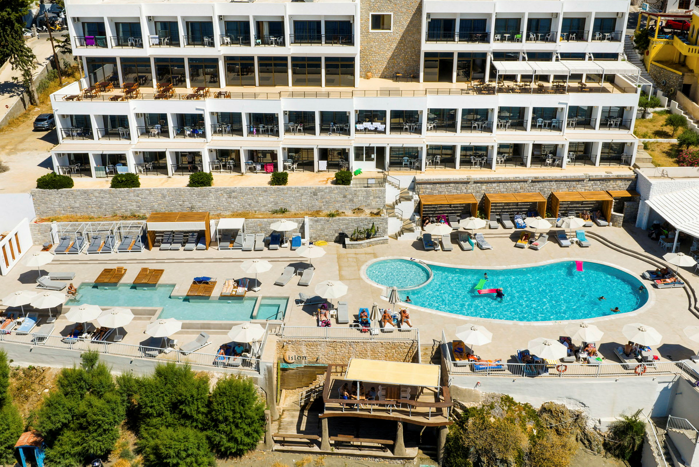 Luftfoto av hotellområde med basseng og solsenger. (AI-generert tekst)