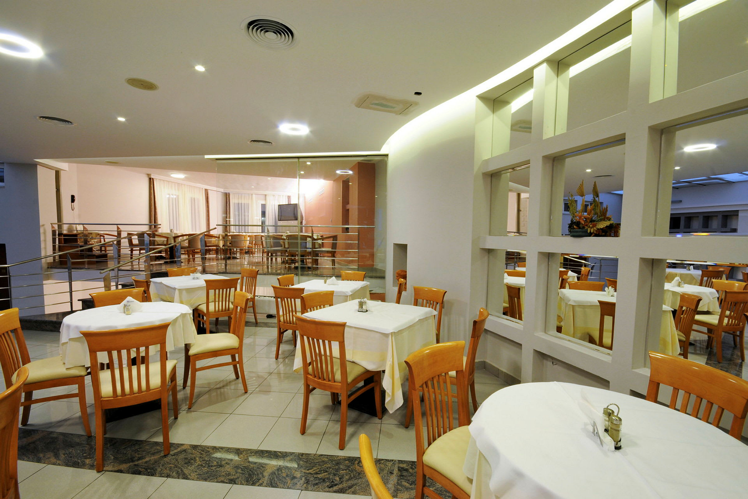 Bilde av en restaurant med oppdekkede trebord og stoler. (AI-generert tekst)