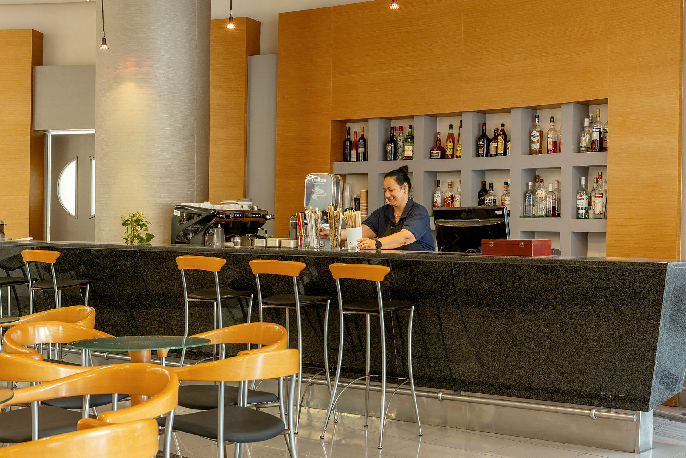 En hotellbar med sitteområde og hyller fylt med flasker. (AI-generert tekst)