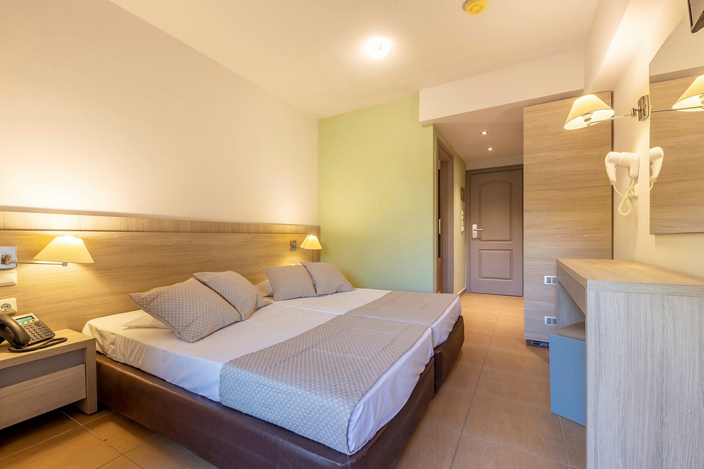 Hotellrom med to enkeltsenger, lamper og skrivebord. (AI-generert tekst)