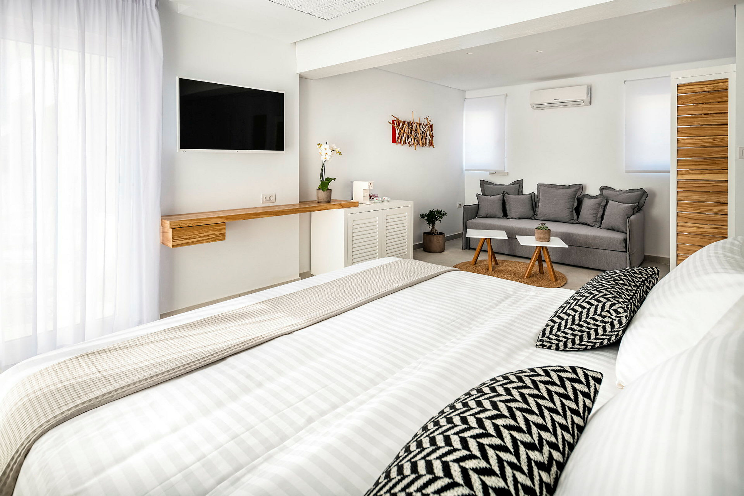 Et lyst, moderne hotellrom med seng, sofa og TV. (AI-generert tekst)
