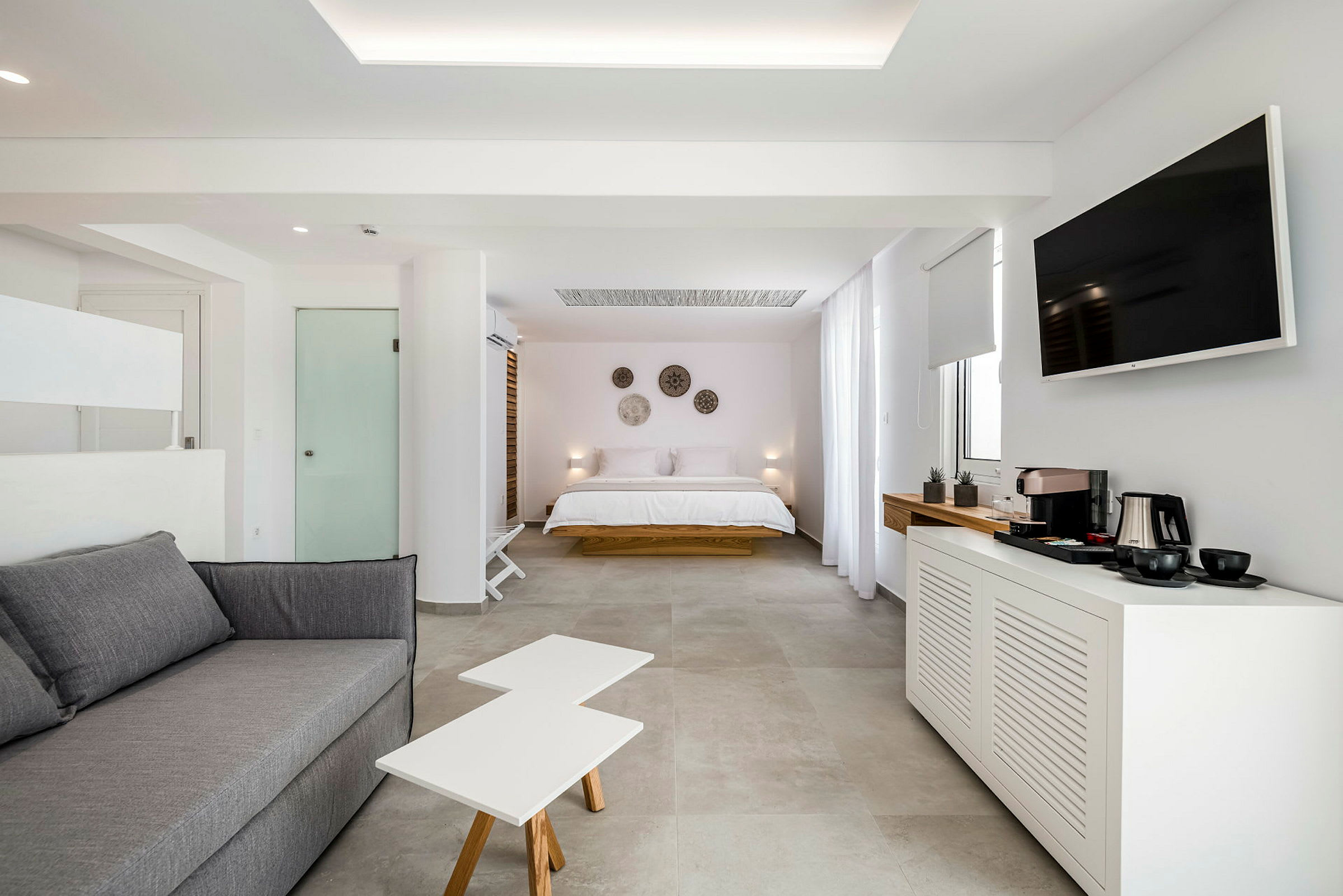 Et moderne hotellrom med seng, sofa, TV og kaffemaskin. (AI-generert tekst)
