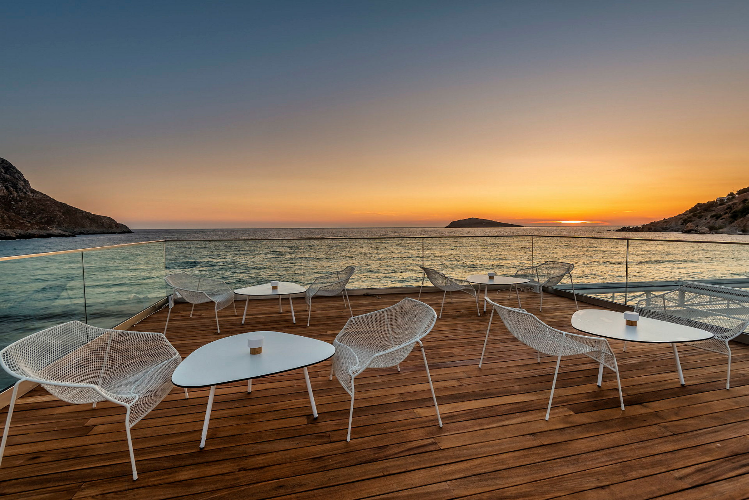 En terrasse med sittemøbler ved havet ved solnedgang. (AI-generert tekst)